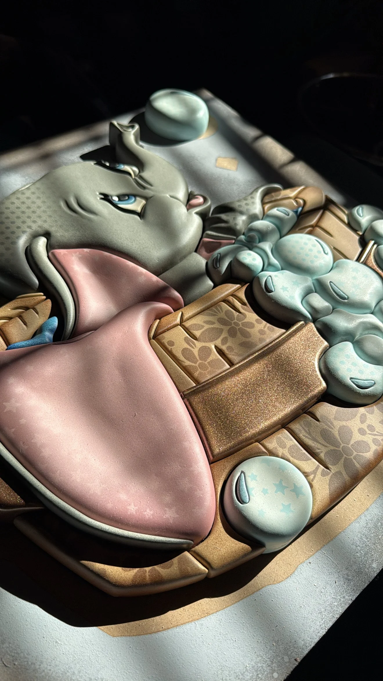 Decorative cake with cartoon bear face, pink tongue, gold accents, and blue and white clouds.