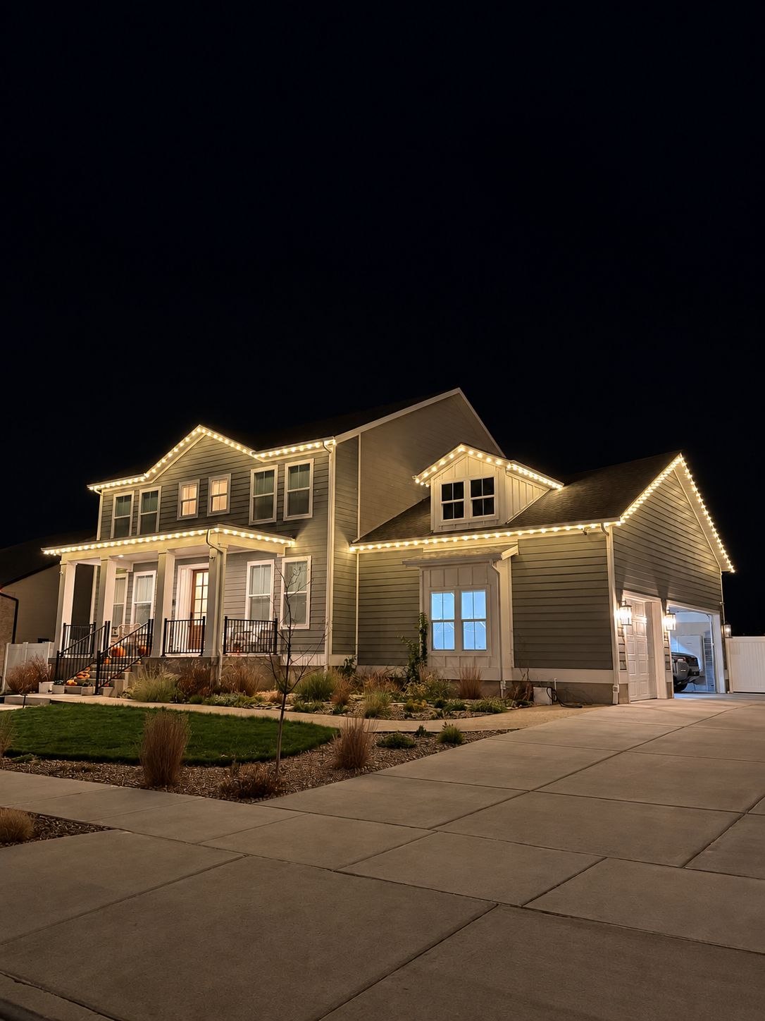 Warm white Christmas lights outlining the roof of a two-story home at night