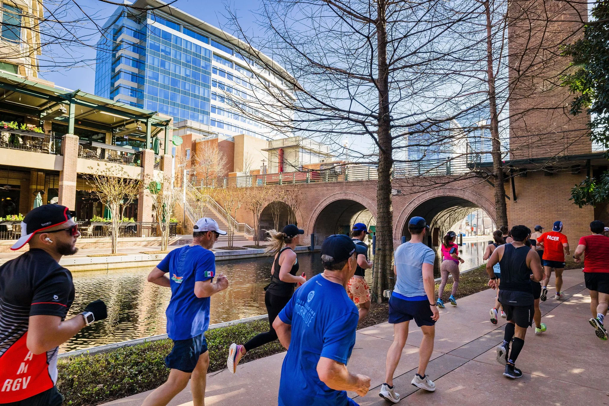 Runners moving together beside The Woodlands Waterway