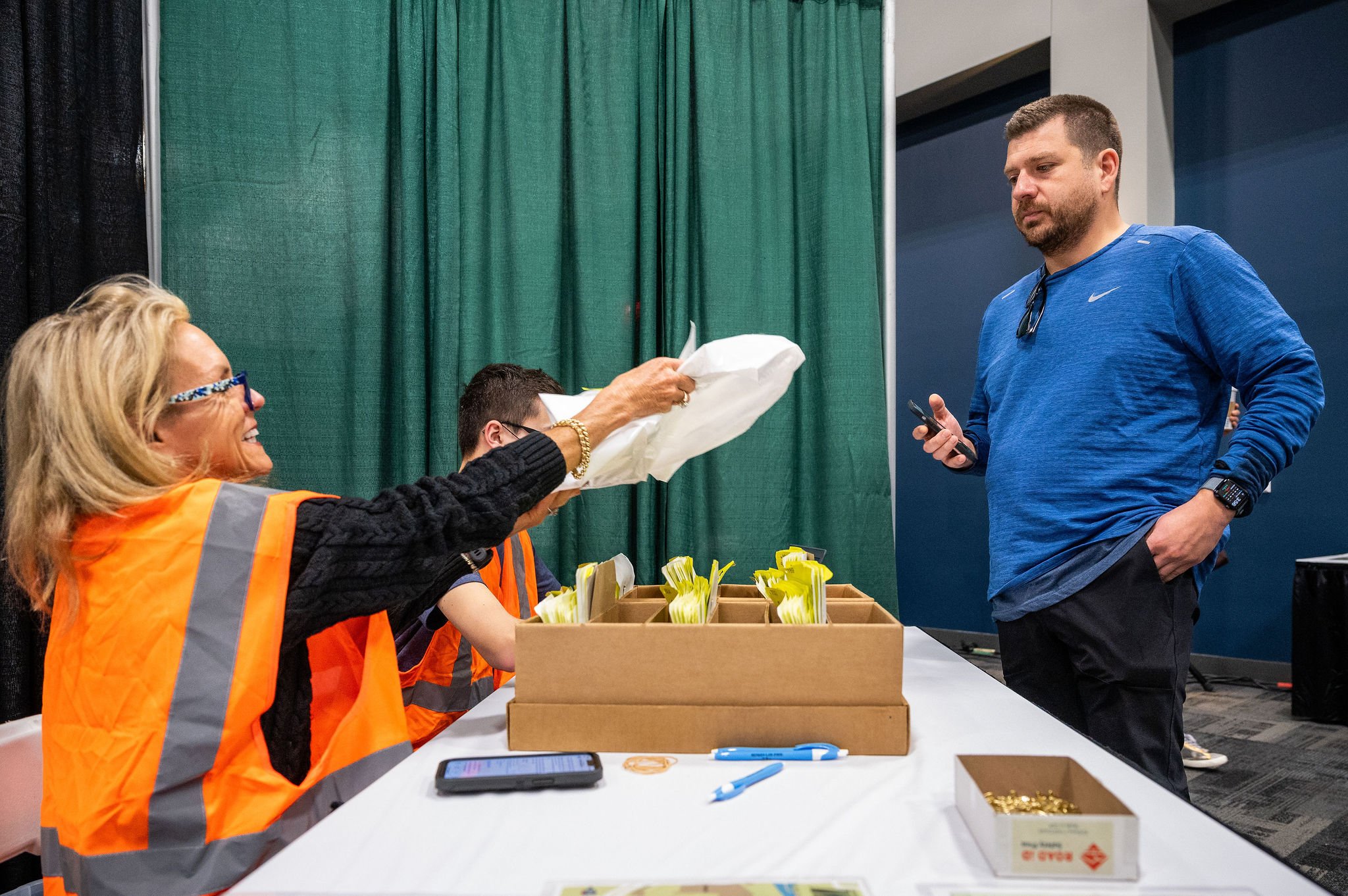 A packet pickup volunteer handing race materials to a runner