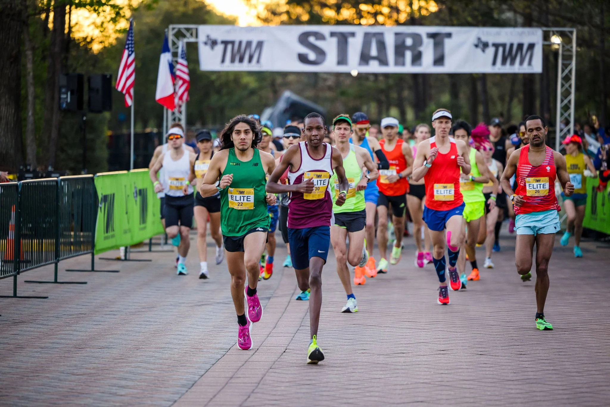Runners gathering beneath The Woodlands Marathon start banner