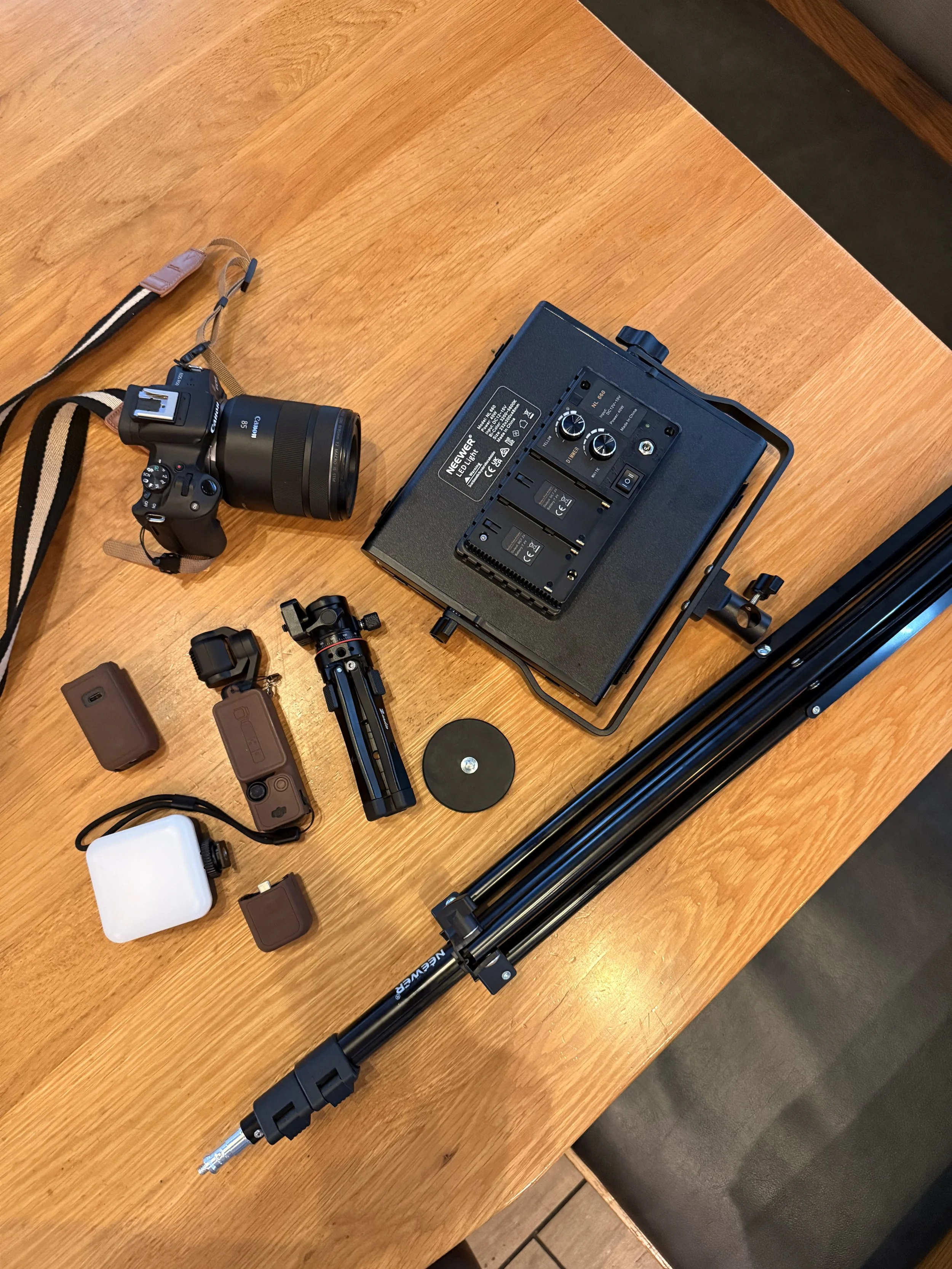 Camera, lenses, LED light panel and tripod laid out on a wooden table for a Poppy House Media photo and video shoot