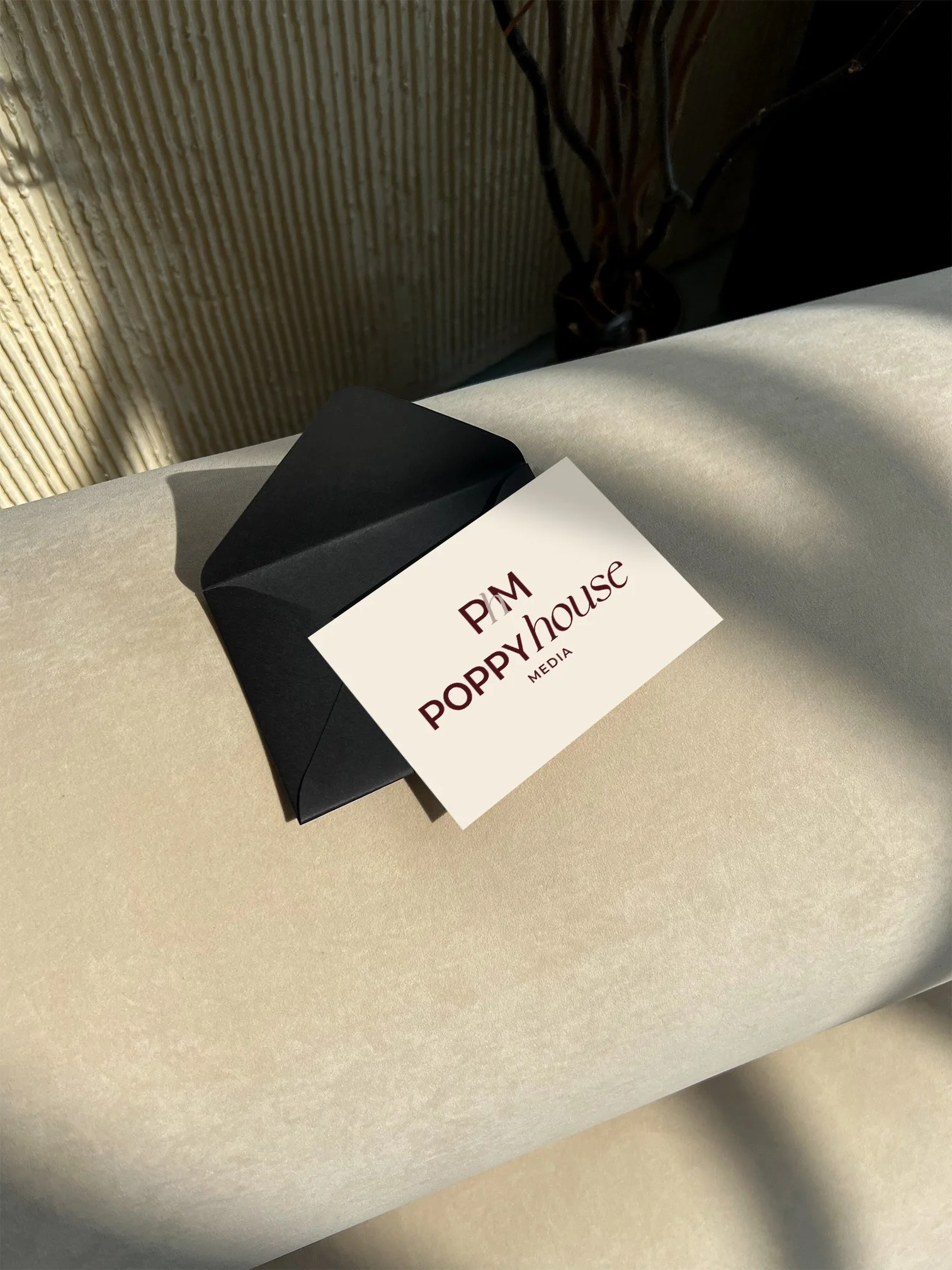 Poppy House Media business card on a cream sofa in soft afternoon light