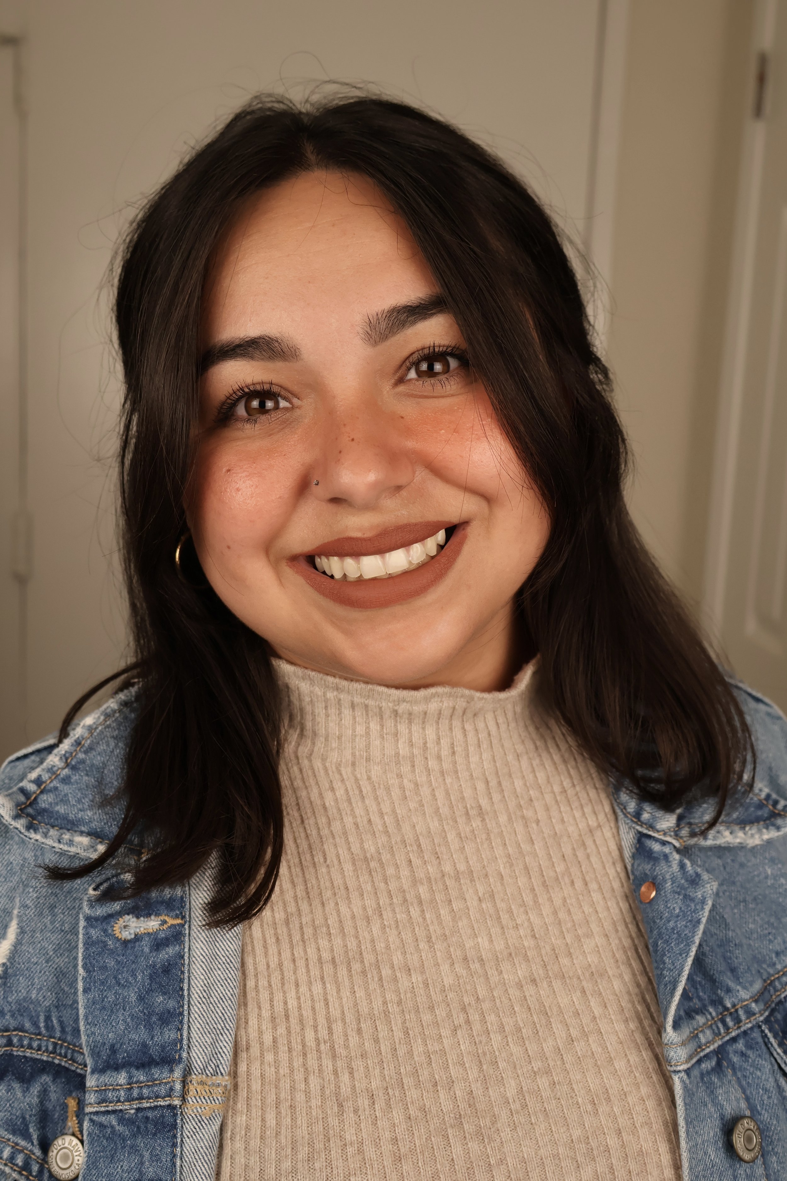 Delia Stuhr, founder of Poppy House Media, smiling in a denim jacket and cream sweater