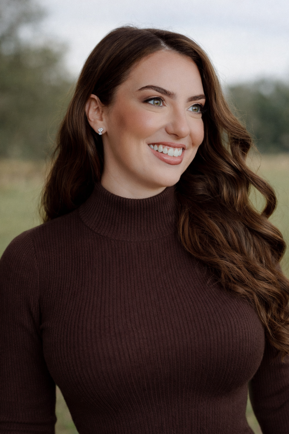 Lexi, founder of The OCD Collective - therapist and OCD educator - smiling outdoors in a brown turtleneck