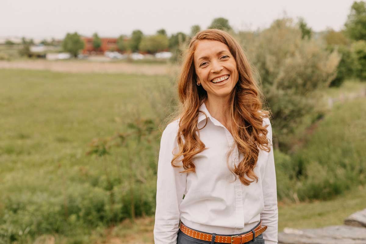 Dr. Morrison Taylor smiling outdoors in a park or natural setting, wearing a white button-up shirt and a brown belt.