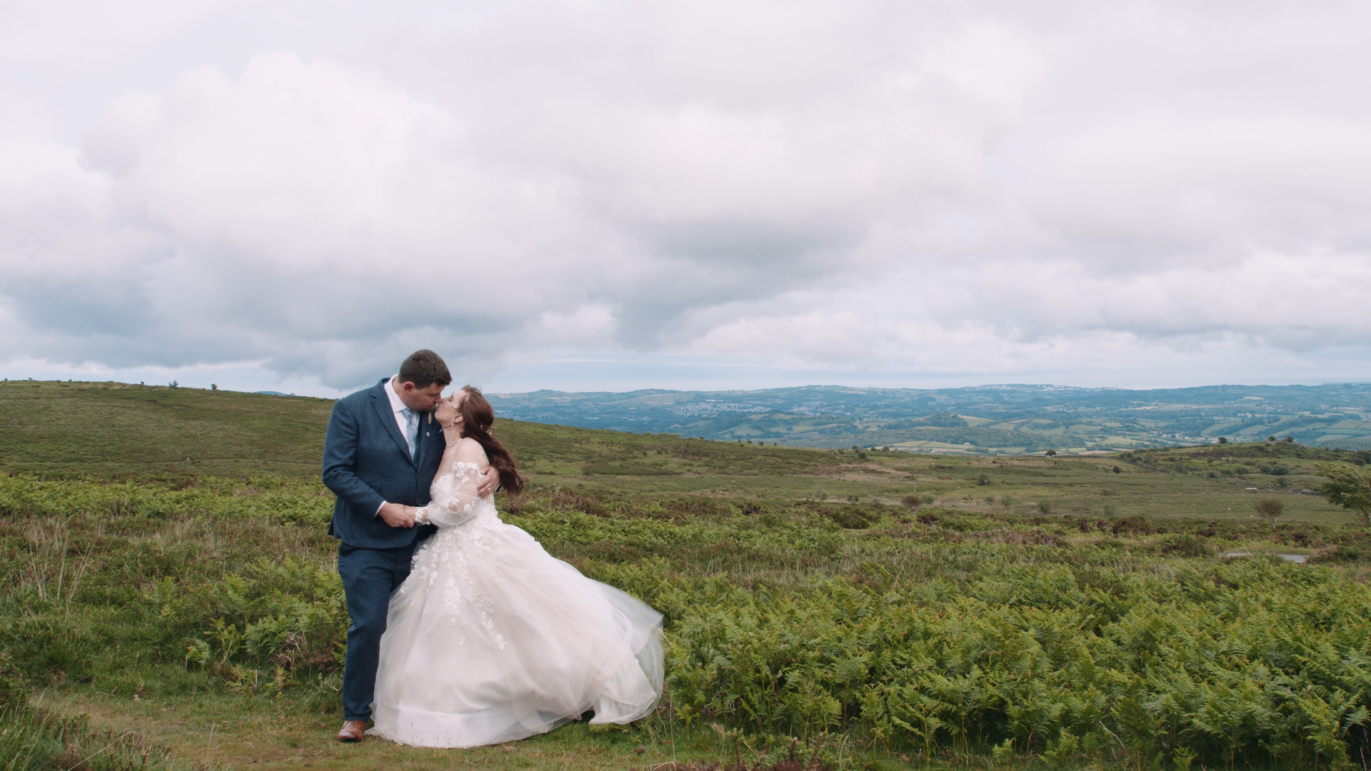 Groom (left) and bride (right) share a kiss in the Devon moors.