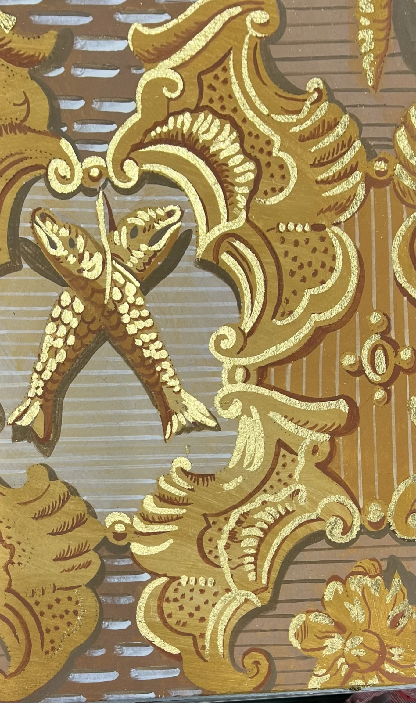 Ein detailreiches goldfarbenes Muster mit floralen und ornamentalen Elementen, typisch für Barock- oder Rokokostil, auf einem braunen Hintergrund.