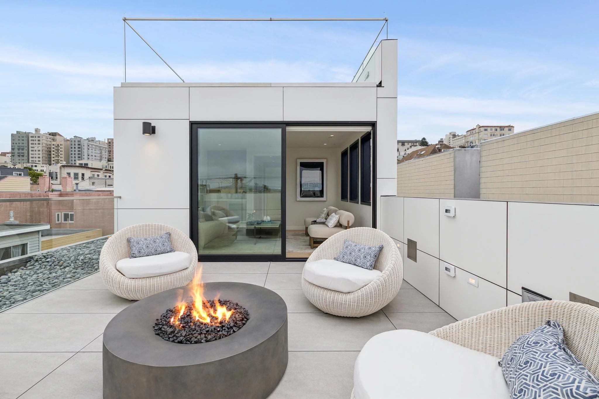 Modern rooftop terrace with outdoor seating, a fire pit, and cityscape view.