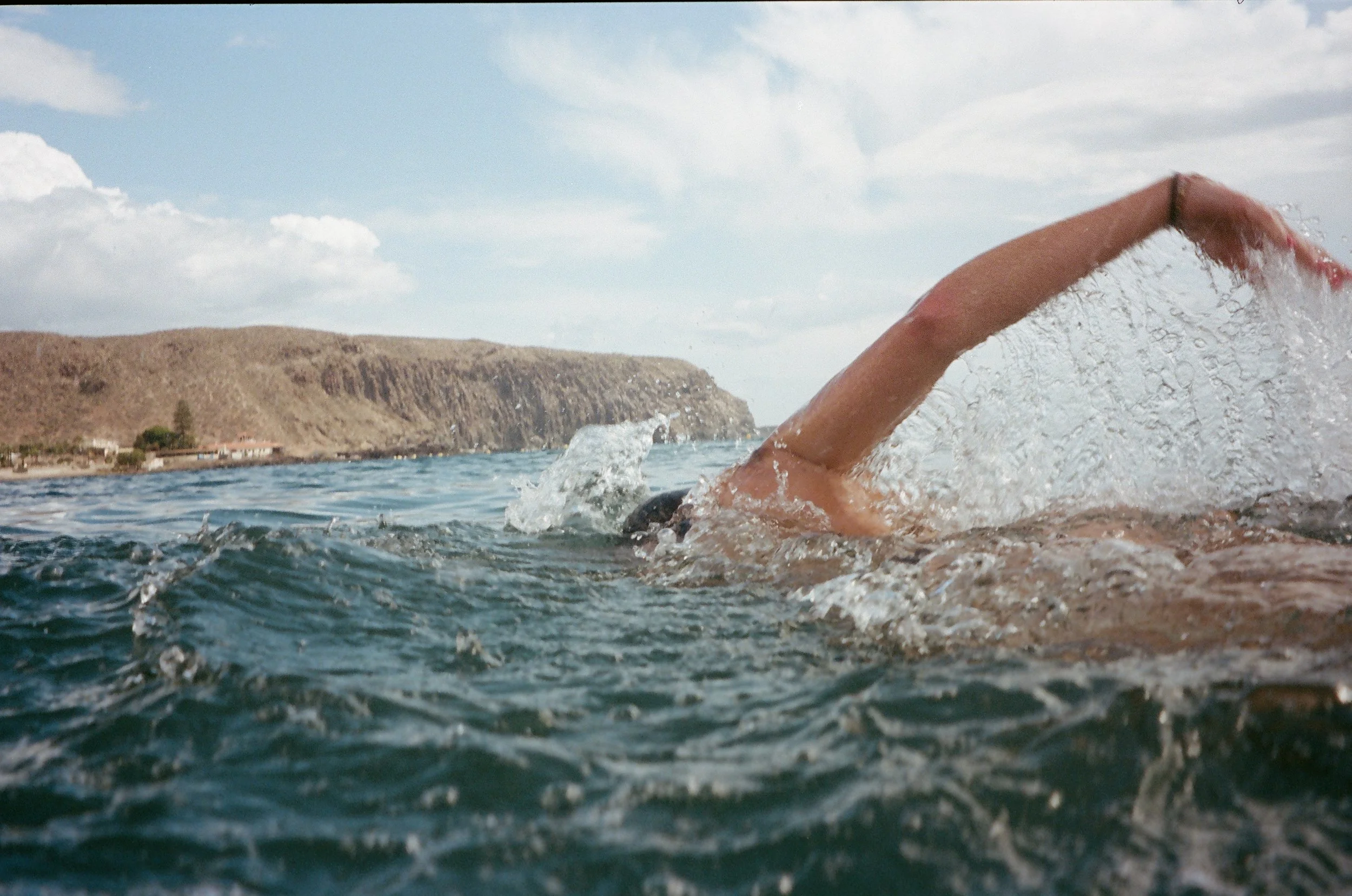 A person swimming in the water with their arm extended forward and water splashing around.