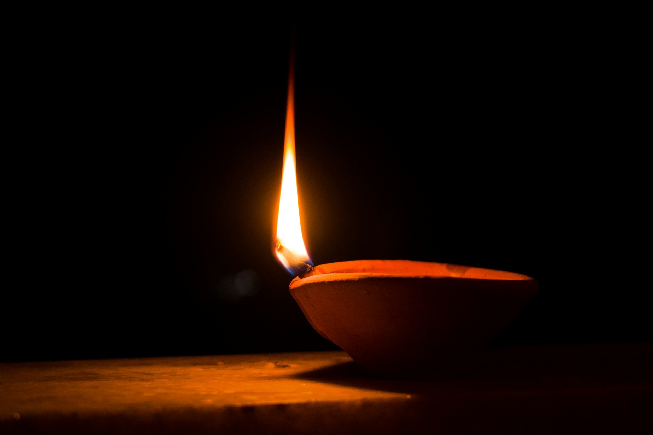 Close-up of a lit candle flame burning in a dark setting.