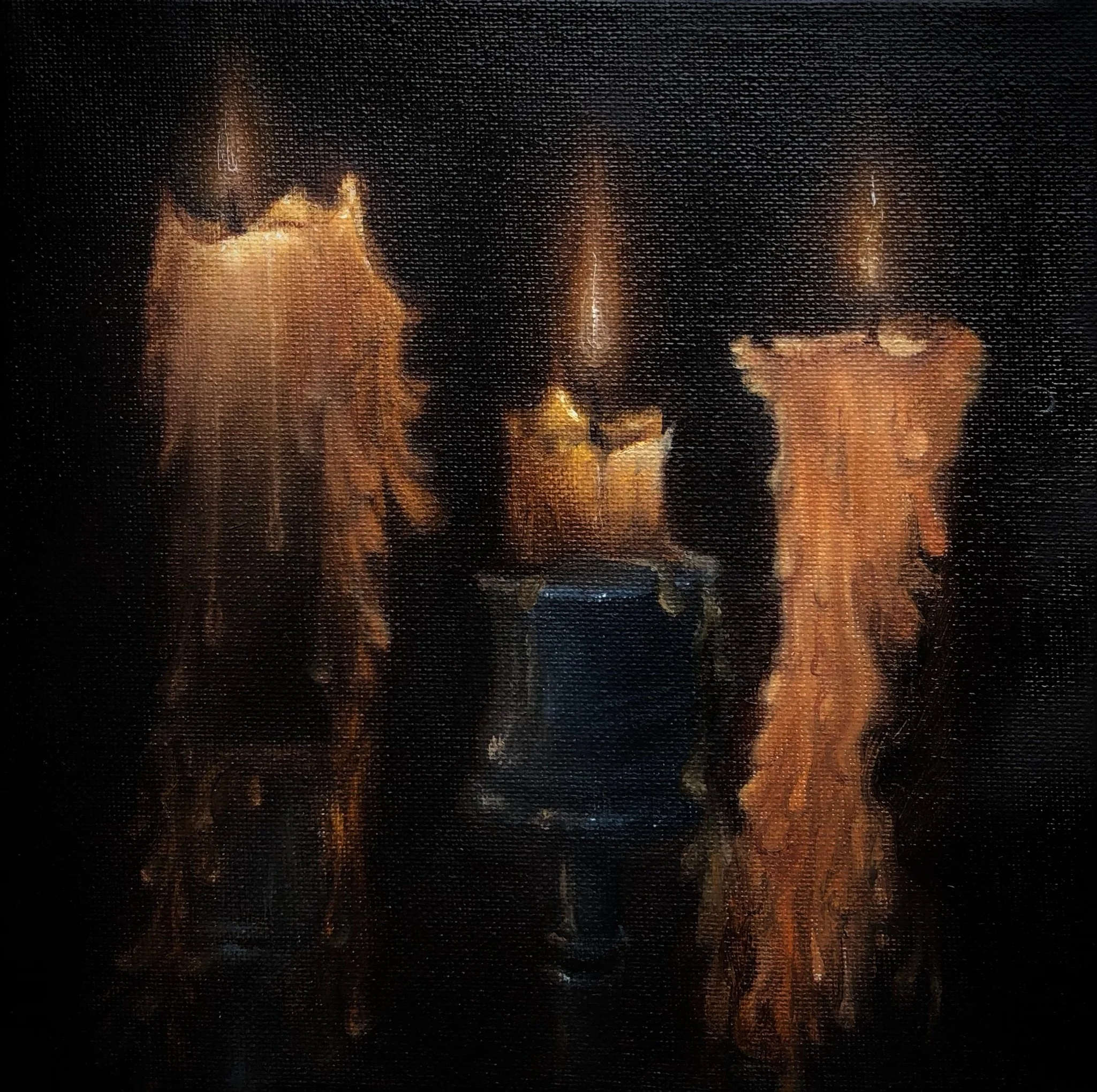 A photo of a fireplace with glowing orange flames and burning logs behind a glass screen.