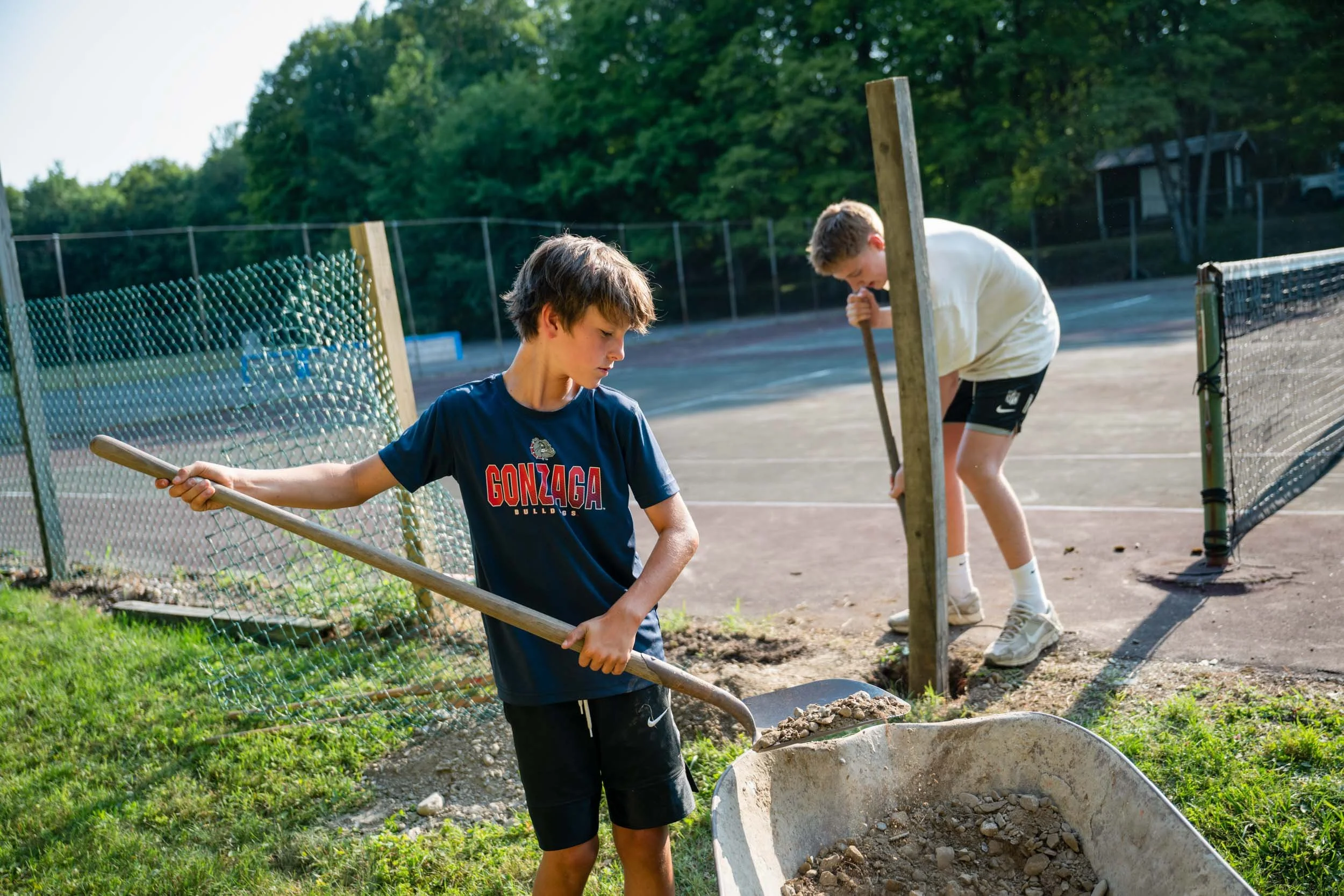 Two boys working together on small work project by the tennis courts.