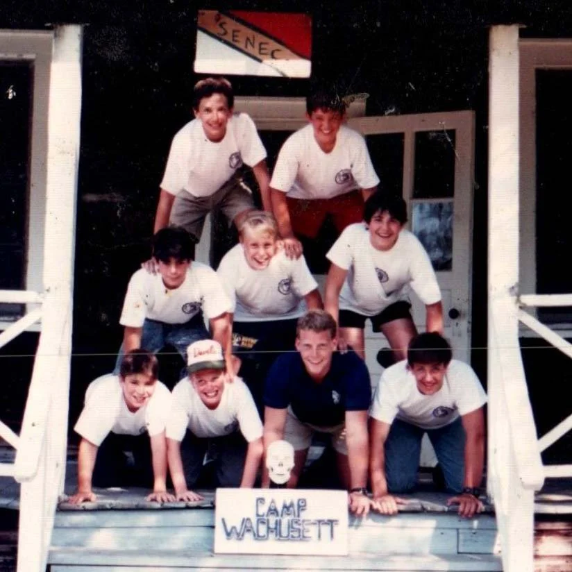 Vintage photos of a cabin group from the 80s making a human pyramid on their cabin porch.
