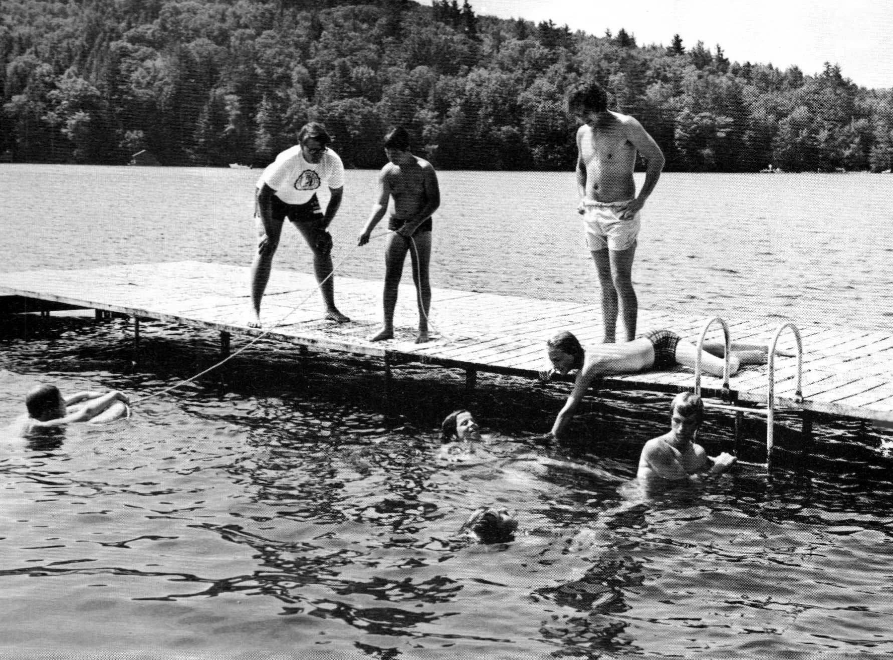 Vintage black and white photo of campers swimming on the lake.