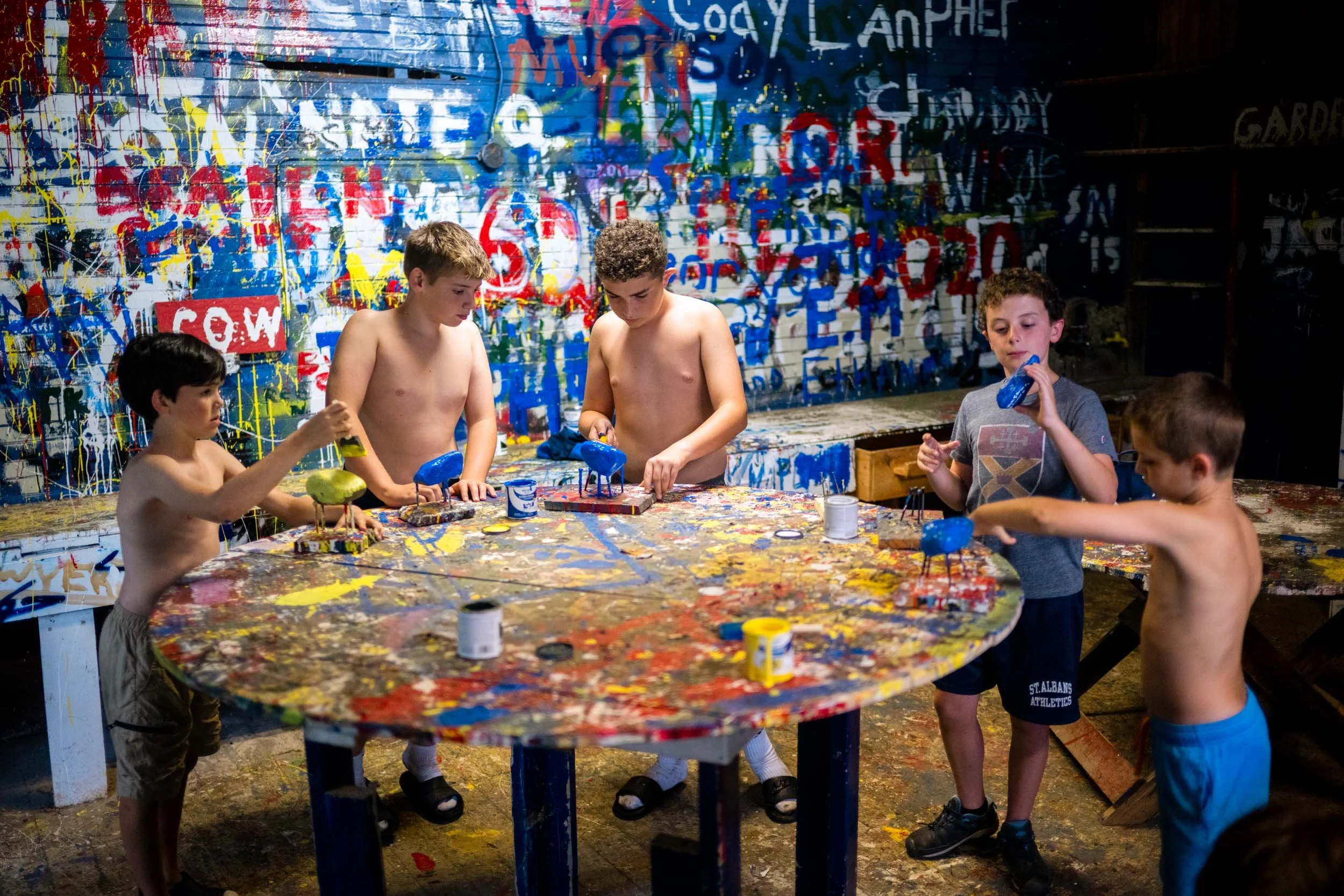 Boys painting rocks in at rustic studio with abstract graffiti-style wall art.