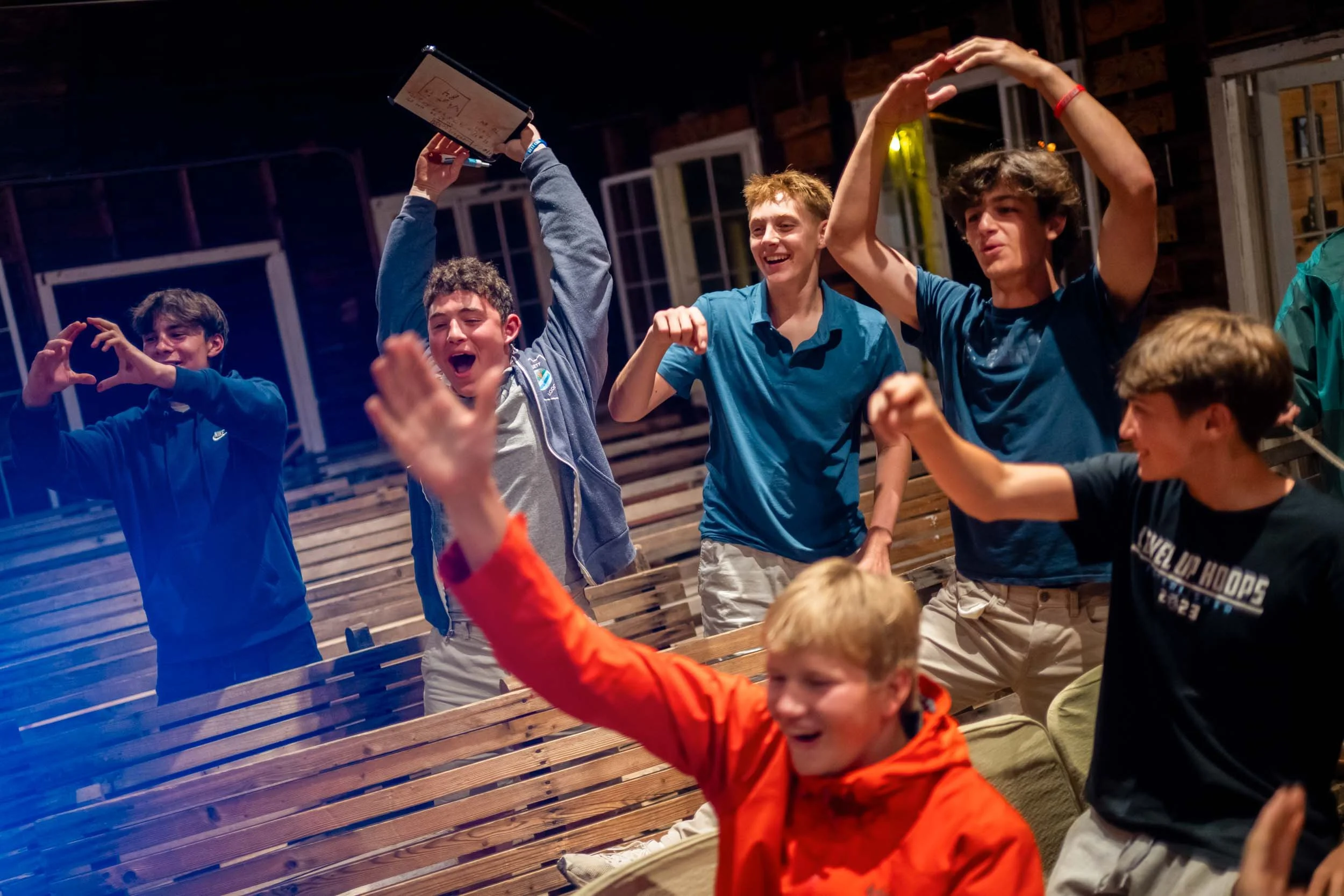 Group of smiling campers and staff at a social gathering in the lodge.