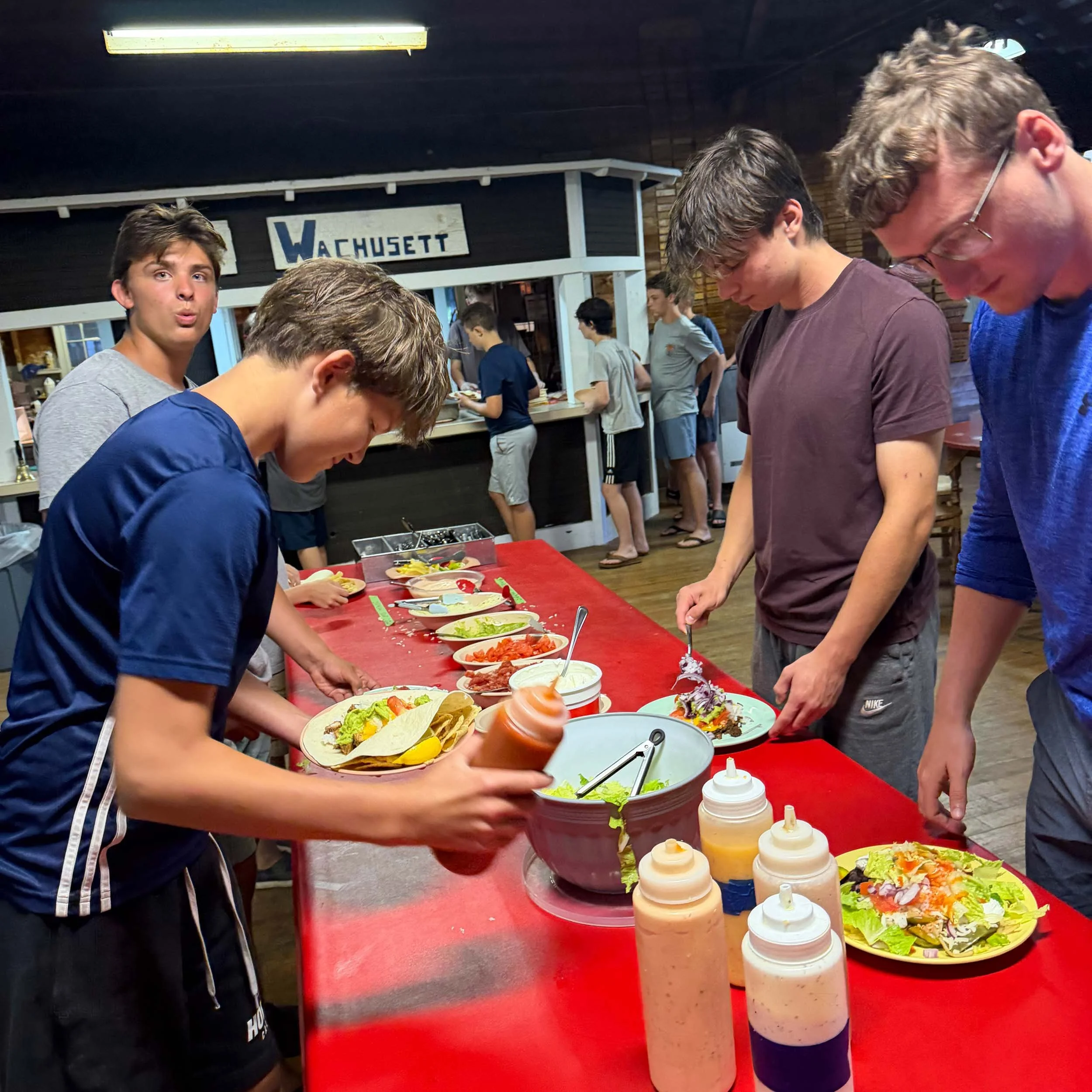 Campers and staff serving themselves food at a buffet in the dining hall.
