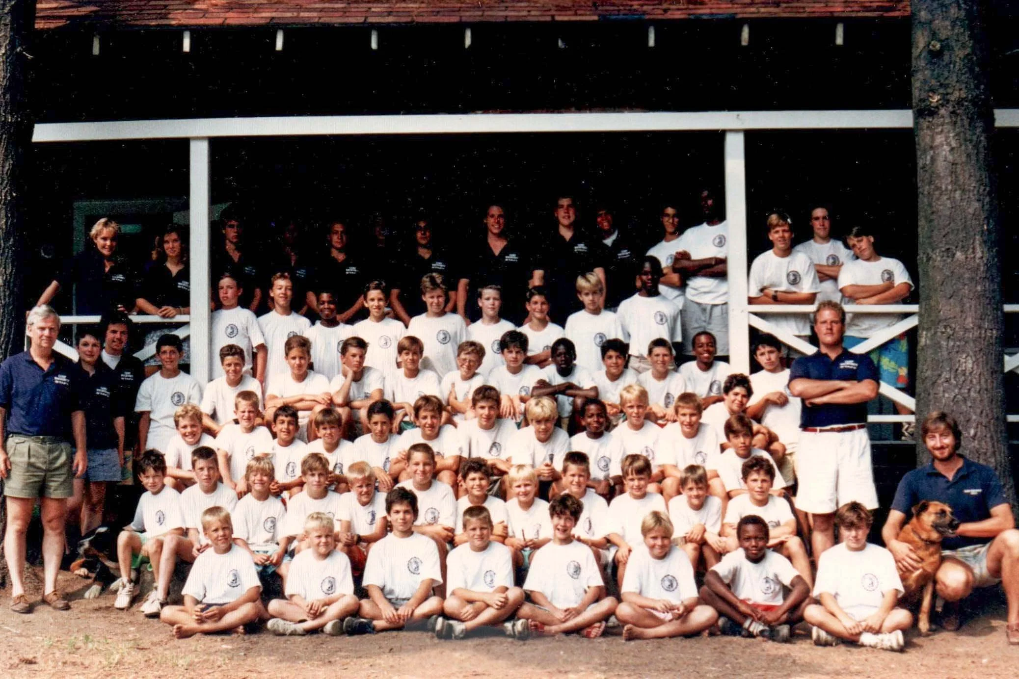 A large group of campers and staff posing outdoors in front of the dinning hall.