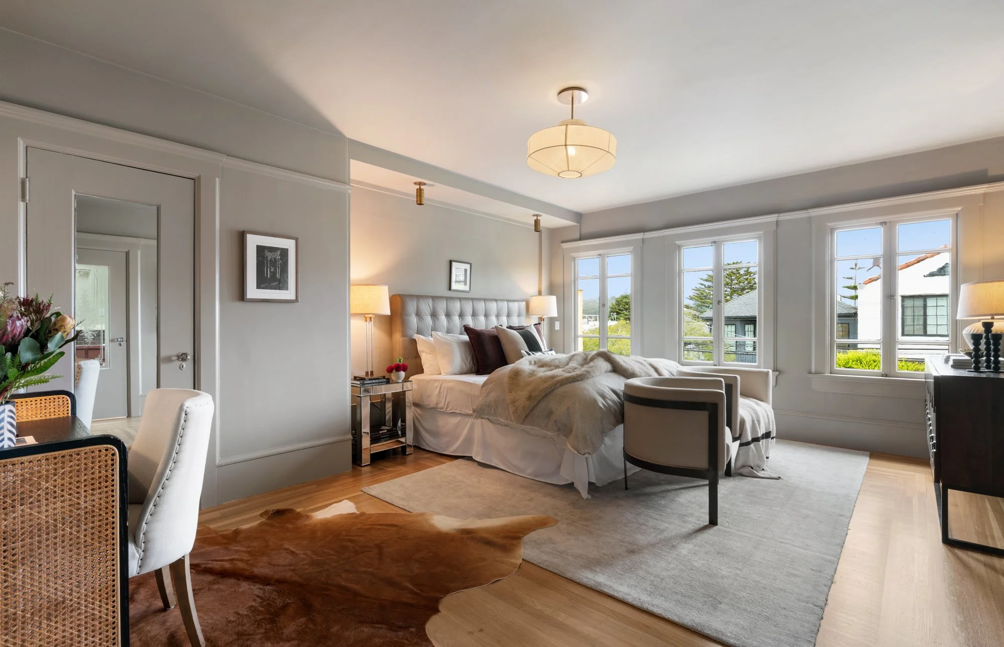 A spacious bedroom with a large bed, multiple windows, and decorative lighting, showcasing a bright and modern interior design.