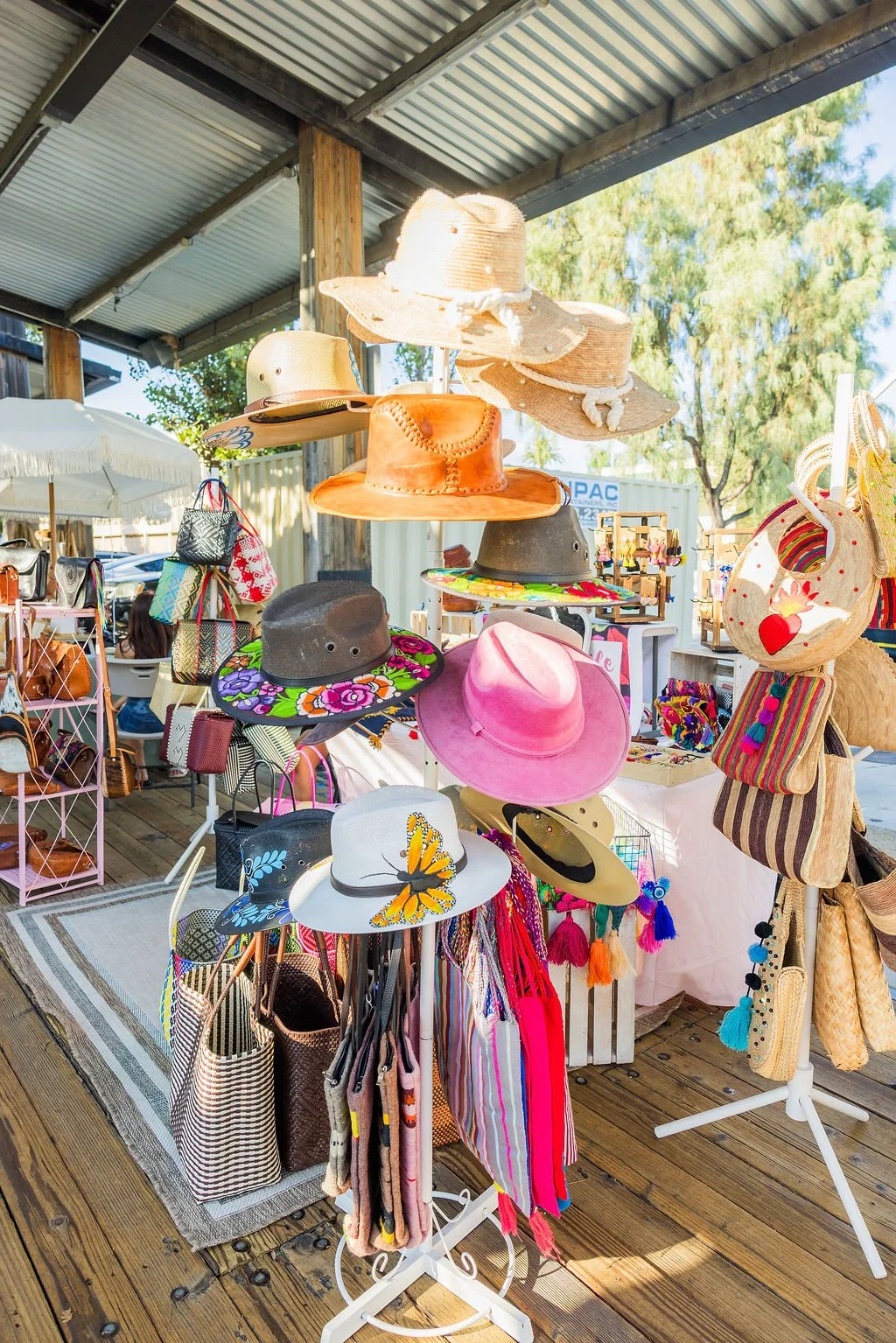 A display of various hats and bags at an outdoor market stall.