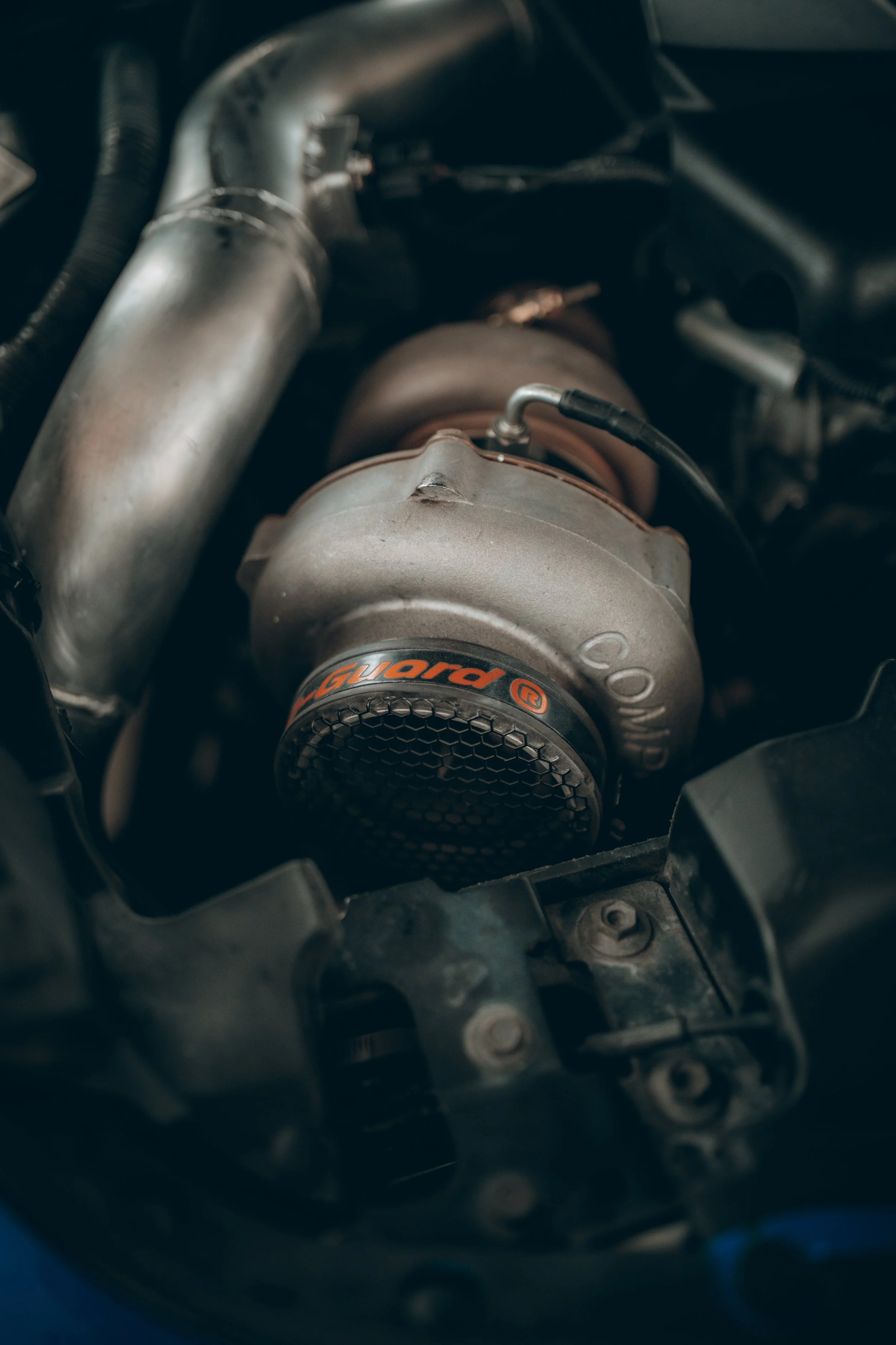 Close-up of a turbocharger and associated air intake components in a car engine bay.