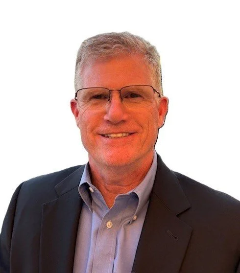Portrait of a middle-aged man with gray hair, wearing glasses, a dark blazer, and a light blue shirt, smiling at the camera.