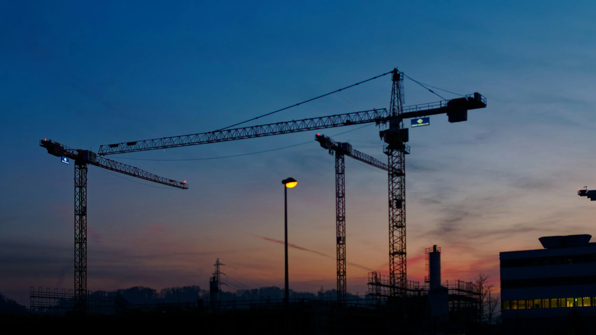 Tower cranes at a commercial construction site at dusk