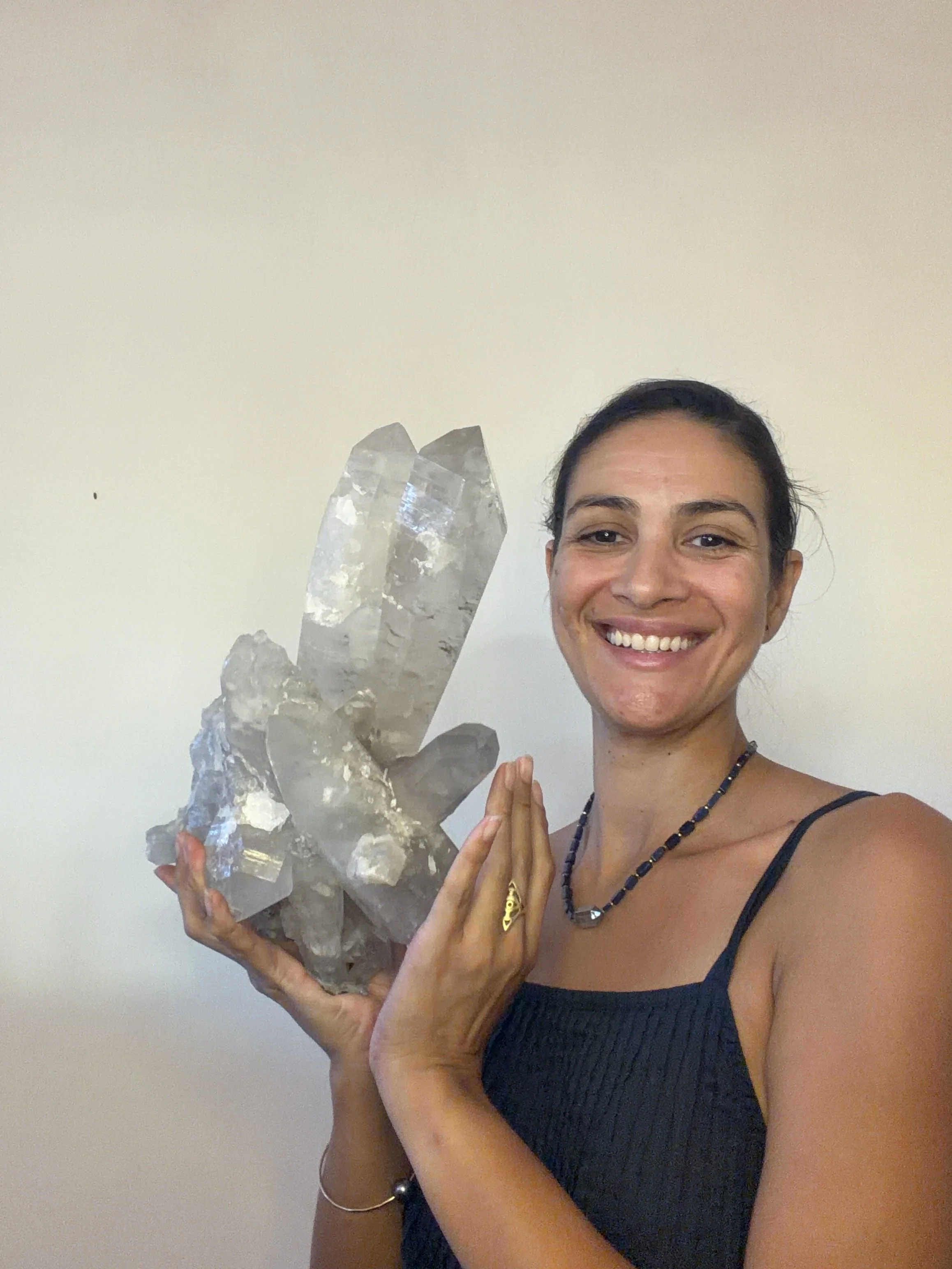 A woman smiling and holding a large cluster of clear quartz crystals.