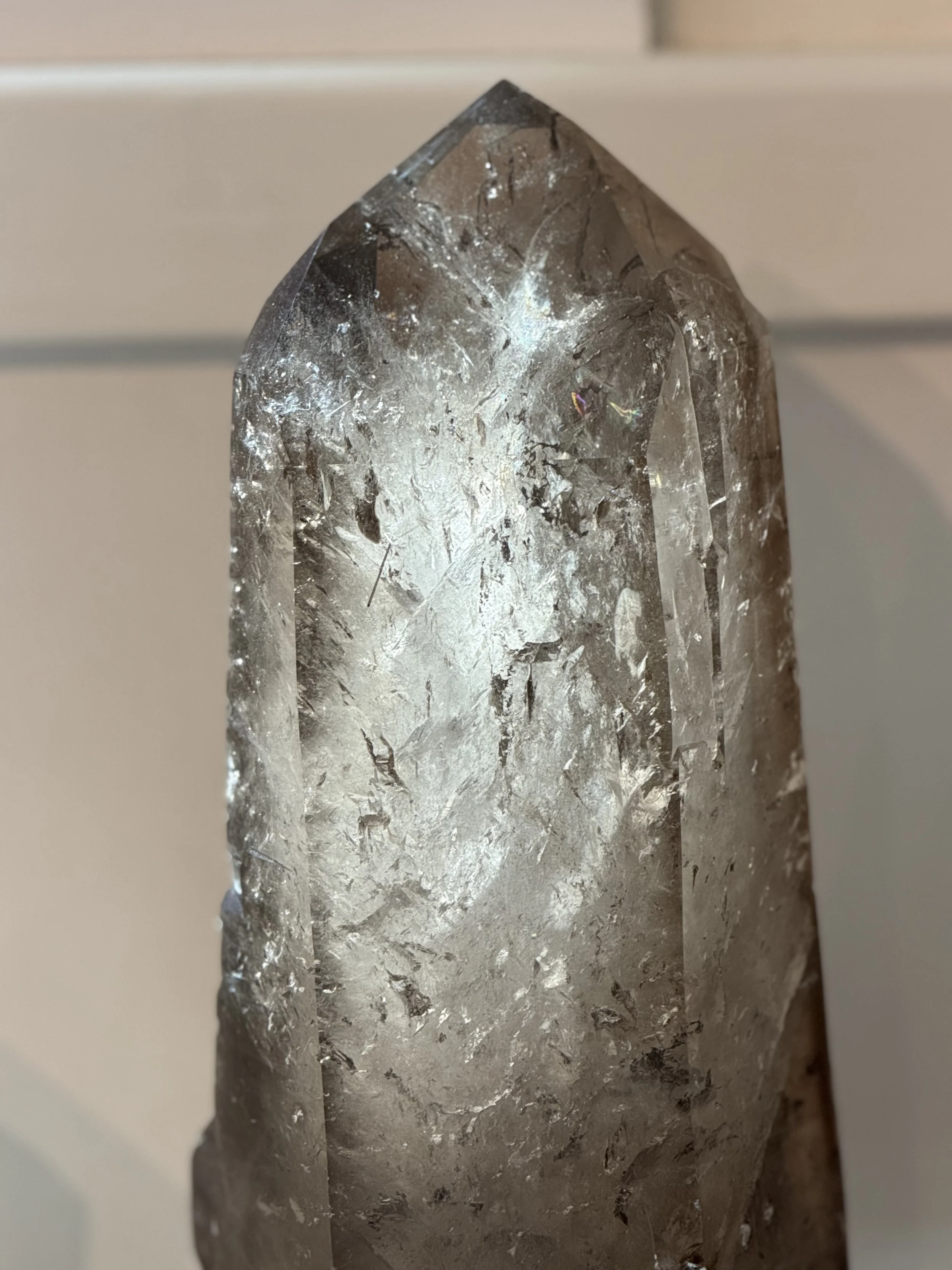 Close-up of a clear quartz crystal with jagged edges and internal fractures, set against a neutral background.