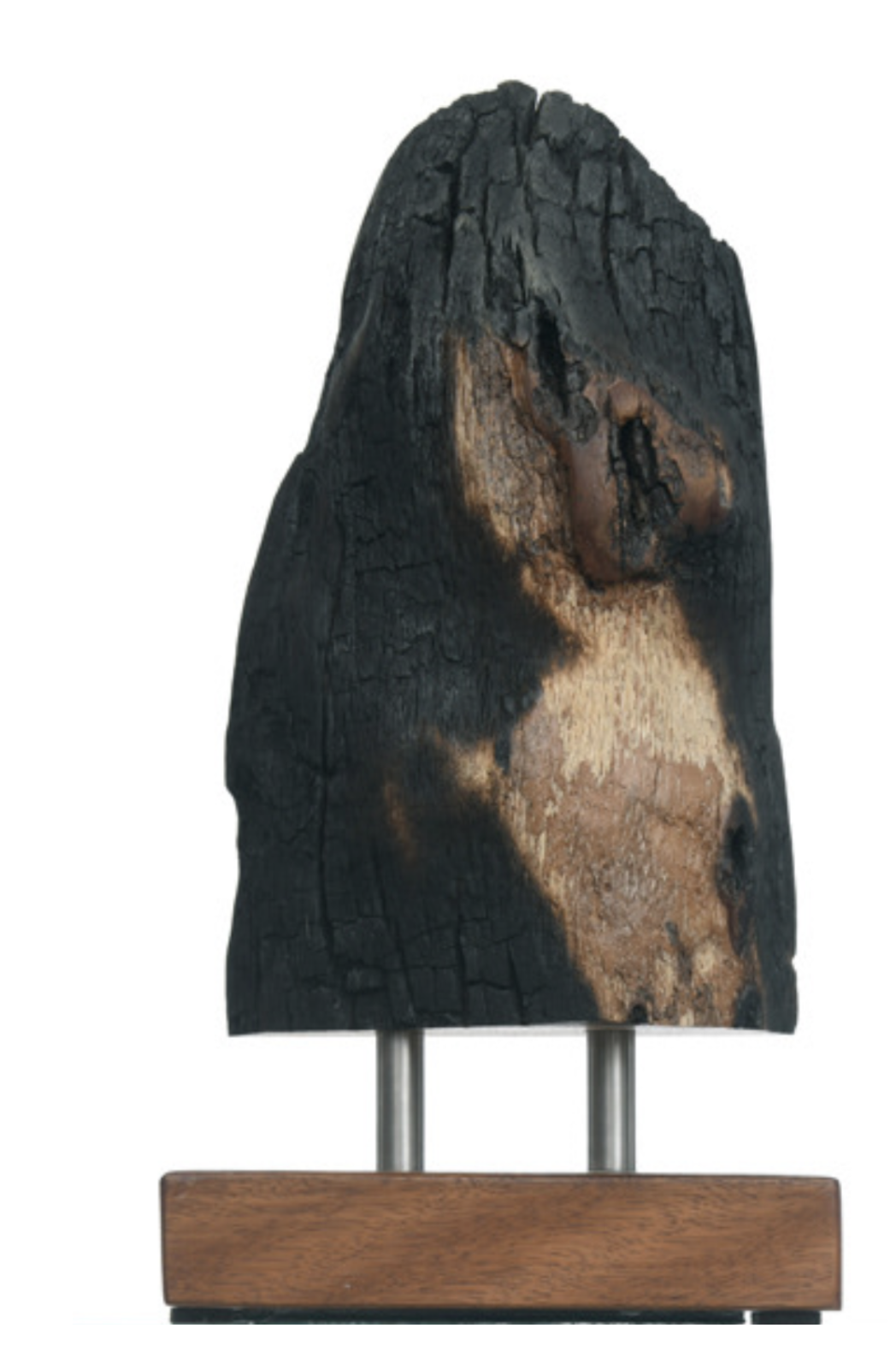 A burnt piece of wood with a painted image of the Virgin Mary on it, propped on two metal supports and a wooden base.