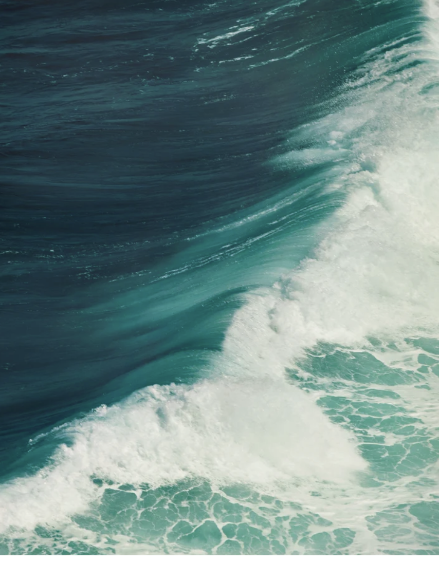 Close-up of a large ocean wave with turquoise water and white foam.
