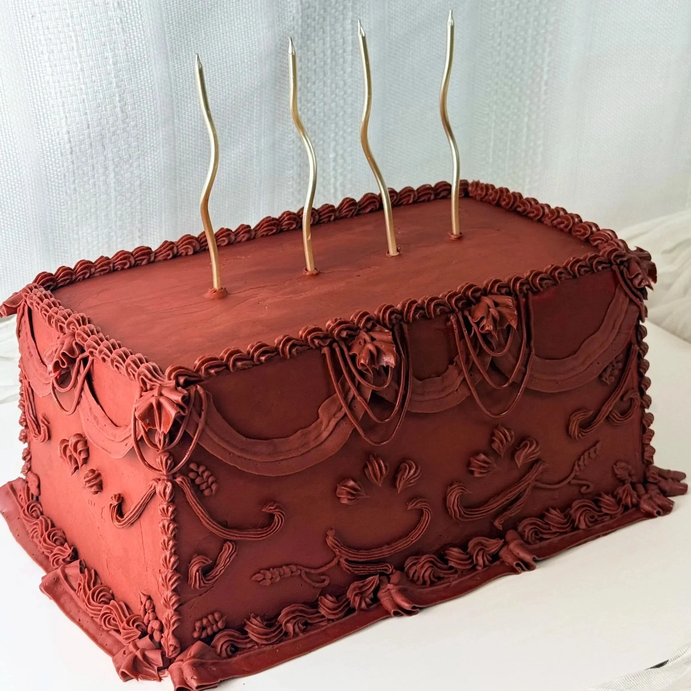 A red velvet cake decorated with rosette piping and a cake topper with sparklers.