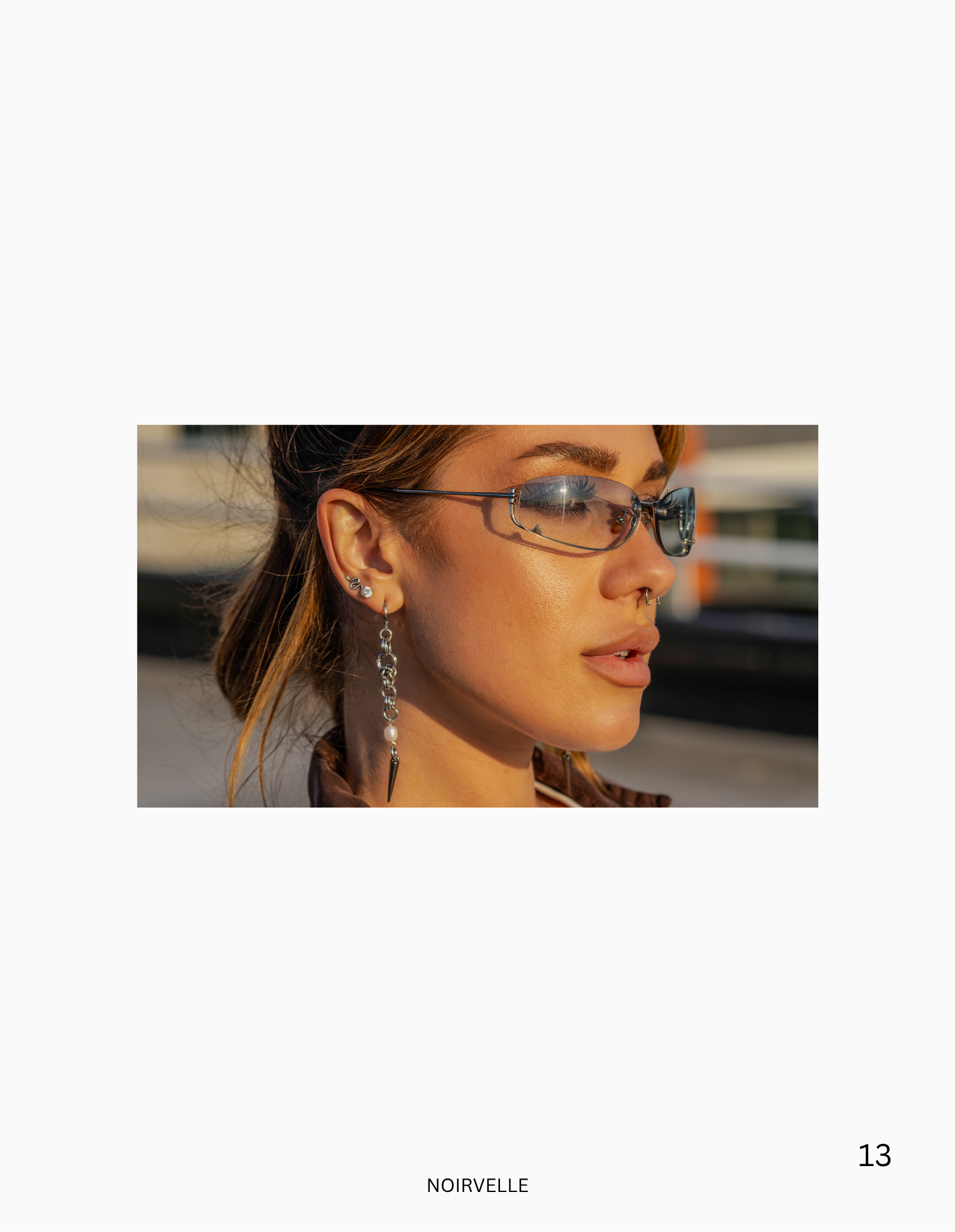 Fashion beauty portrait featuring a female model with statement eyewear and jewelry in natural sunlight.
