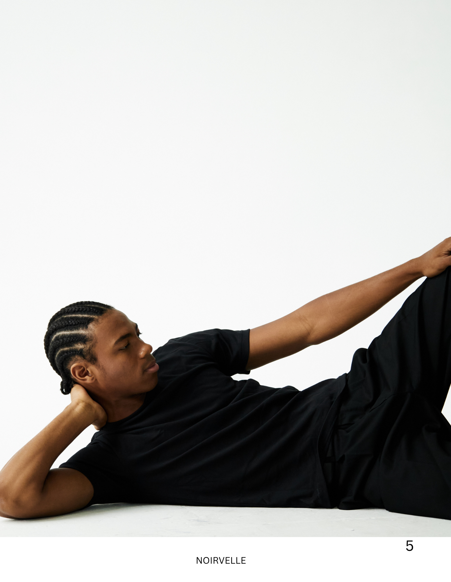 A young woman with braided hair lying on her back, wearing a black shirt, and holding her head with her hands. An arm of a person wearing a dark suit is reaching out towards her, with their hand resting on her head.