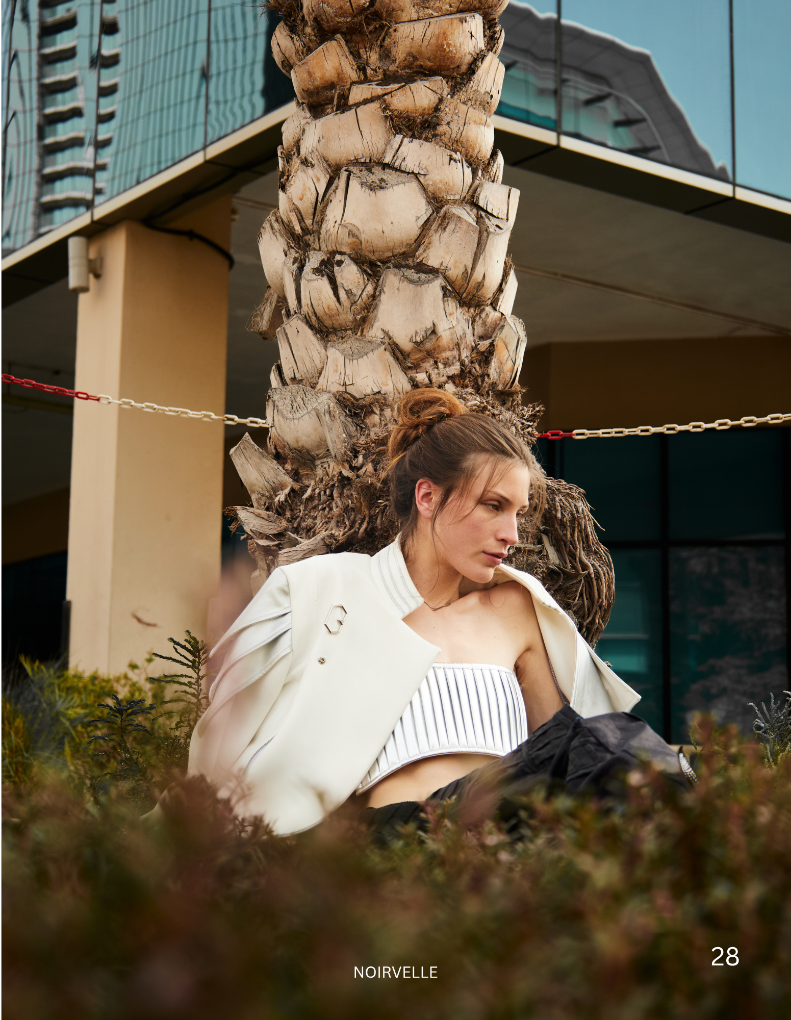 Female model in a white blazer posing outdoors for a NOIRVELLE fashion editorial, photographed by Noirvellel.