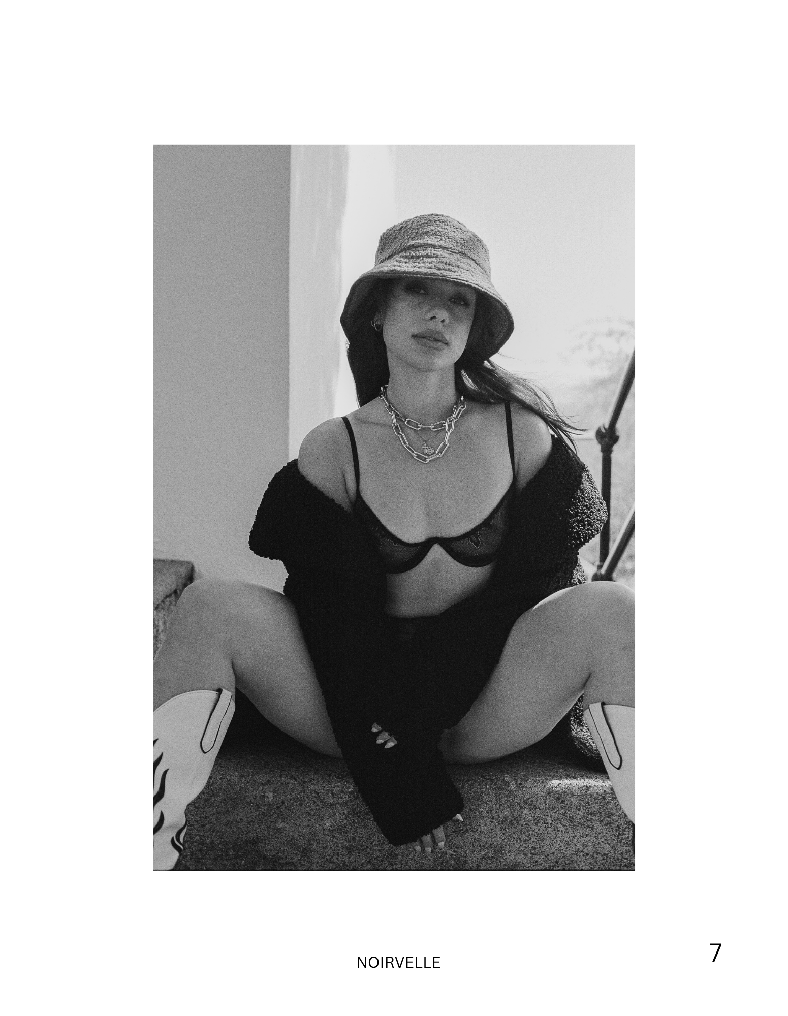 Black-and-white fashion portrait featuring a female model in contemporary styling and a wide-brimmed hat.

