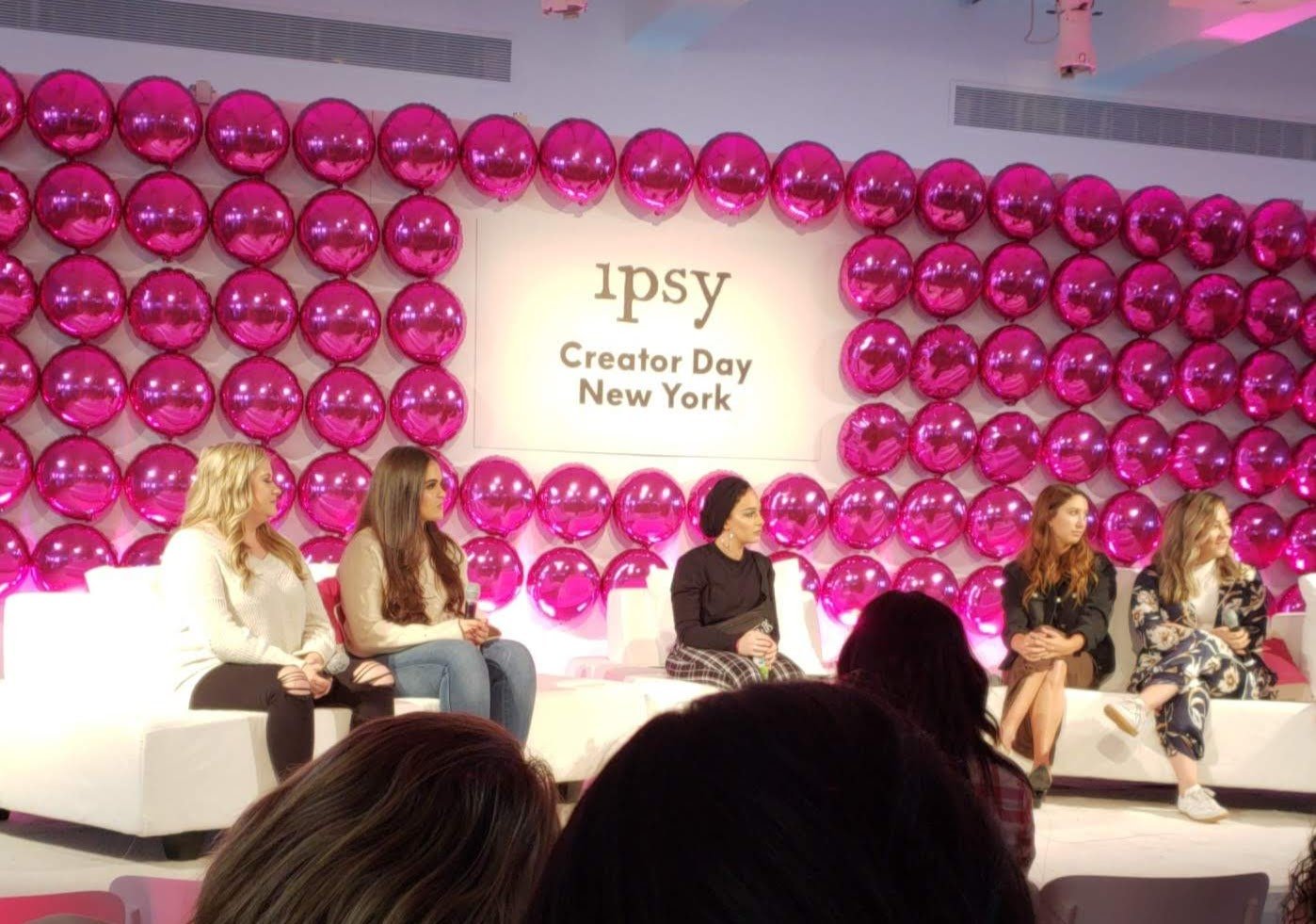 Panel of women seated on couches at Creator Day event in New York, with a backdrop of pink balloons and the logo of ippy.