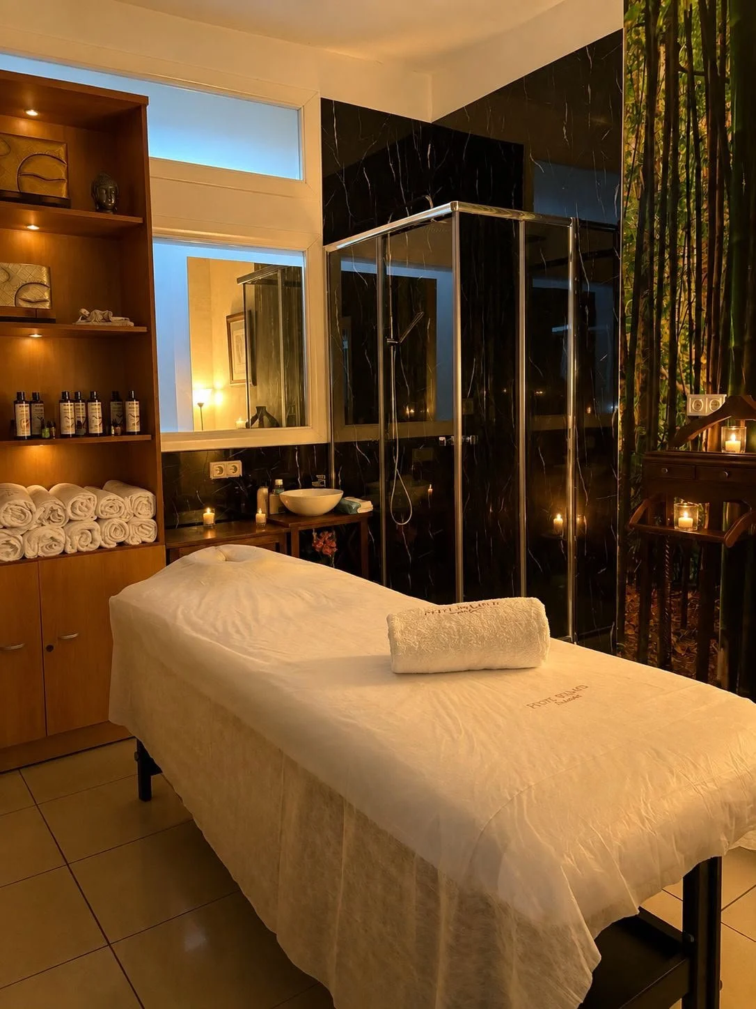 Una habitación de spa con camilla, toallas, productos de belleza, iluminación suave y ambiente relajante.