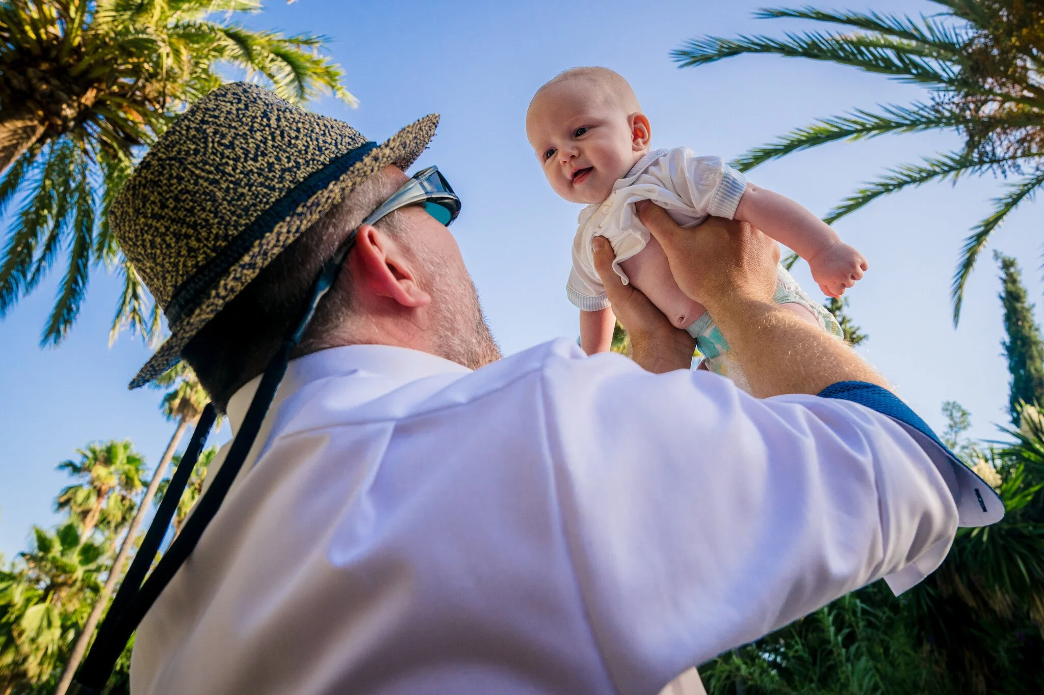 A father lifting his baby into the sunshine during Wolf and Aisley’s wedding