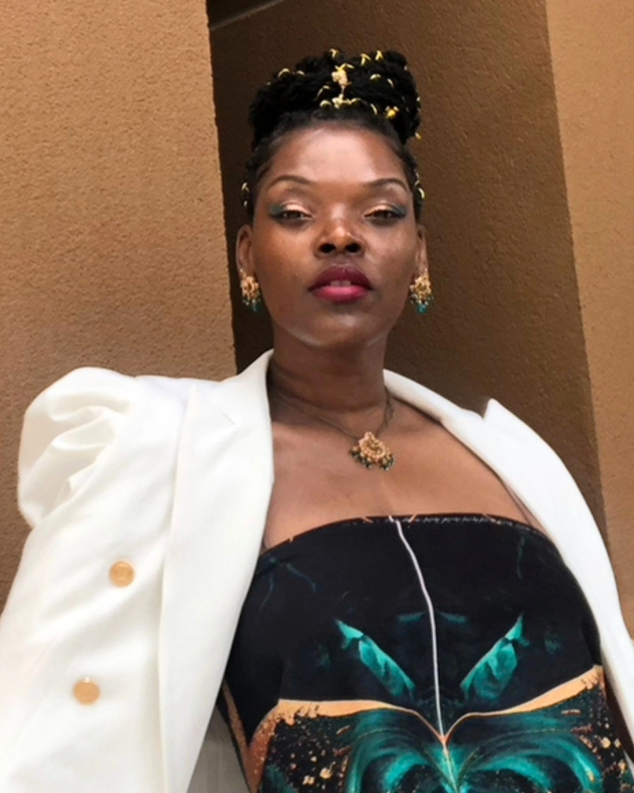 Fashion designer Sheridonna Wilson wearing a structured white blazer and an original Sheridonna Designs printed ensemble.