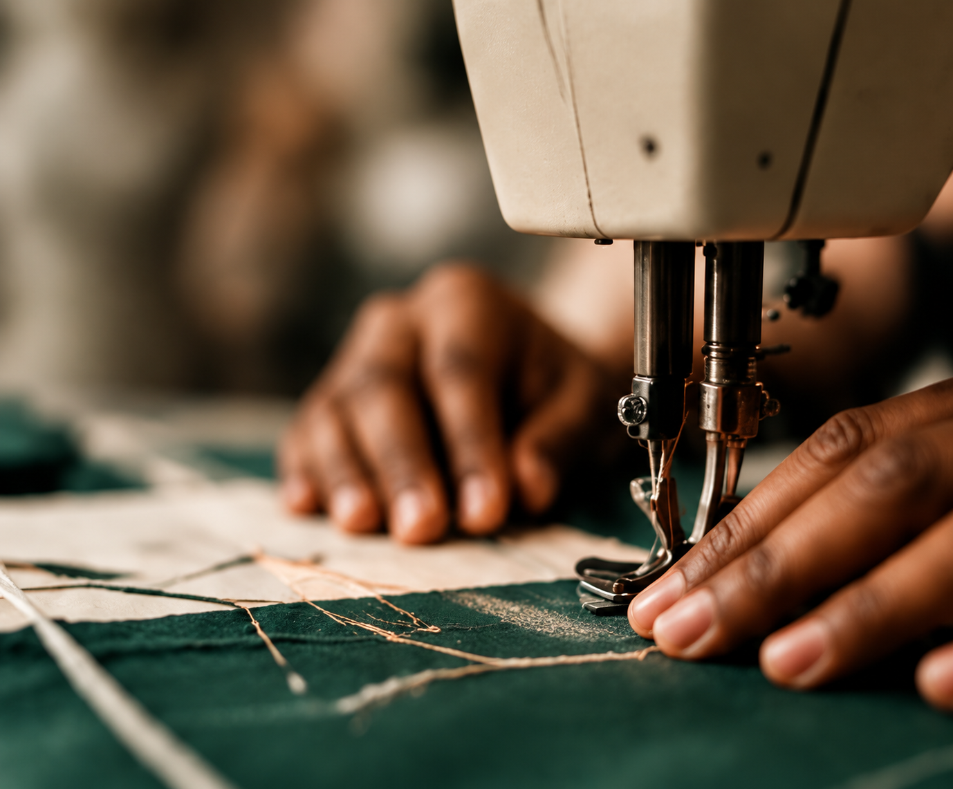 Hands guiding green fabric through a sewing machine, representing hands-on fashion education and skill development.
