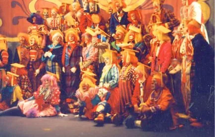 A group of children and adults dressed in colorful clown costumes on stage for a performance.