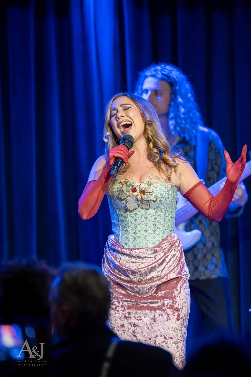 Reinhart sings with her band behind her in the blue-lit room.