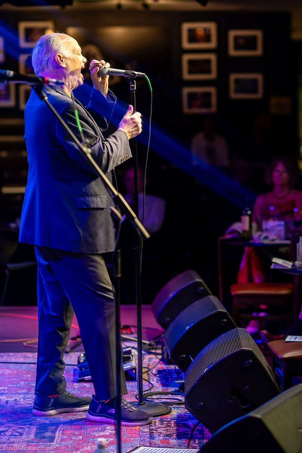 Curtis Salgado sings into a microphone under blue stage lighting at Middle C Jazz in Charlotte.