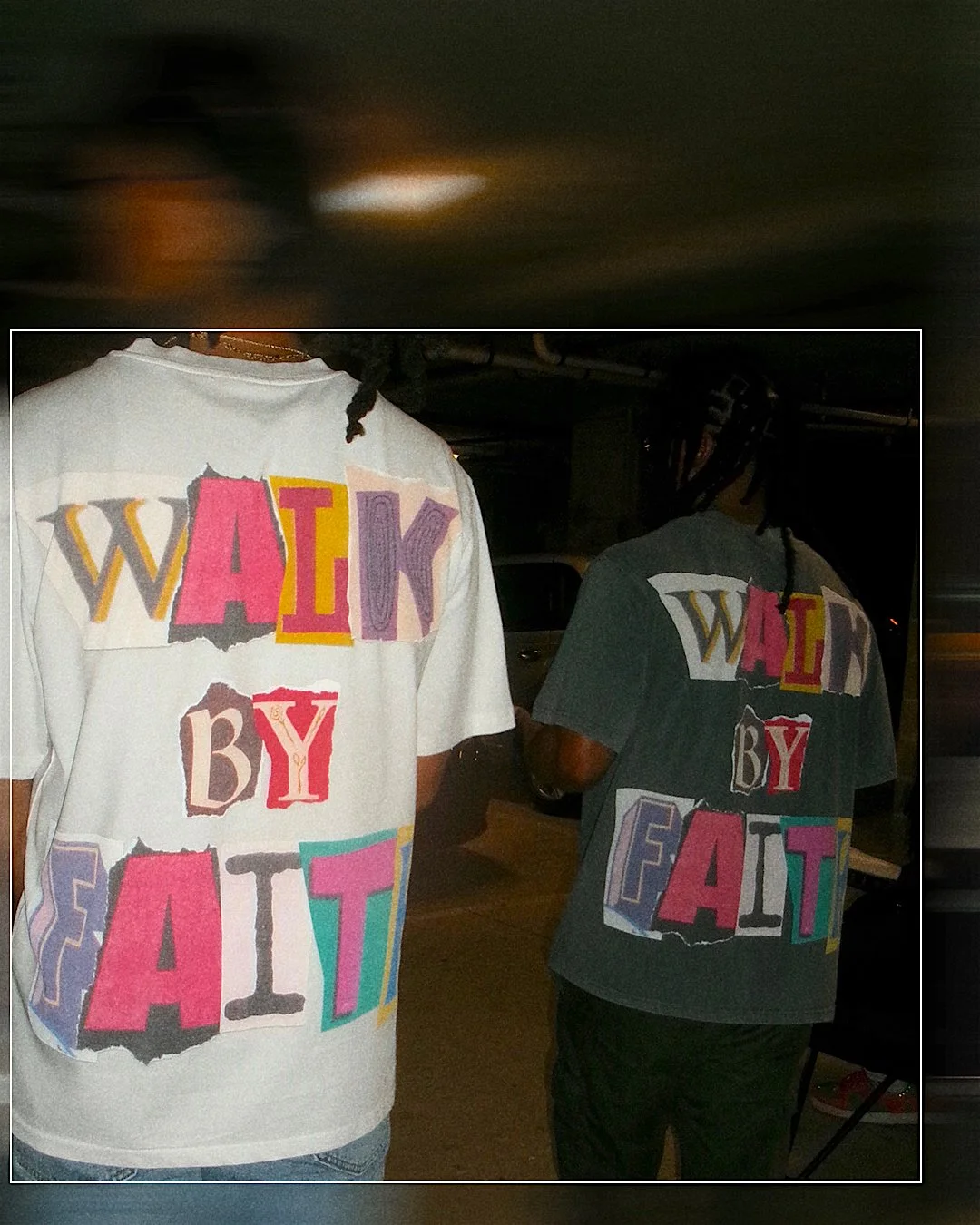 Two people wearing colorful t-shirts with the phrase "WALK BY FAITH" in large, cut-out style letters, seen from behind in a dimly lit parking lot.