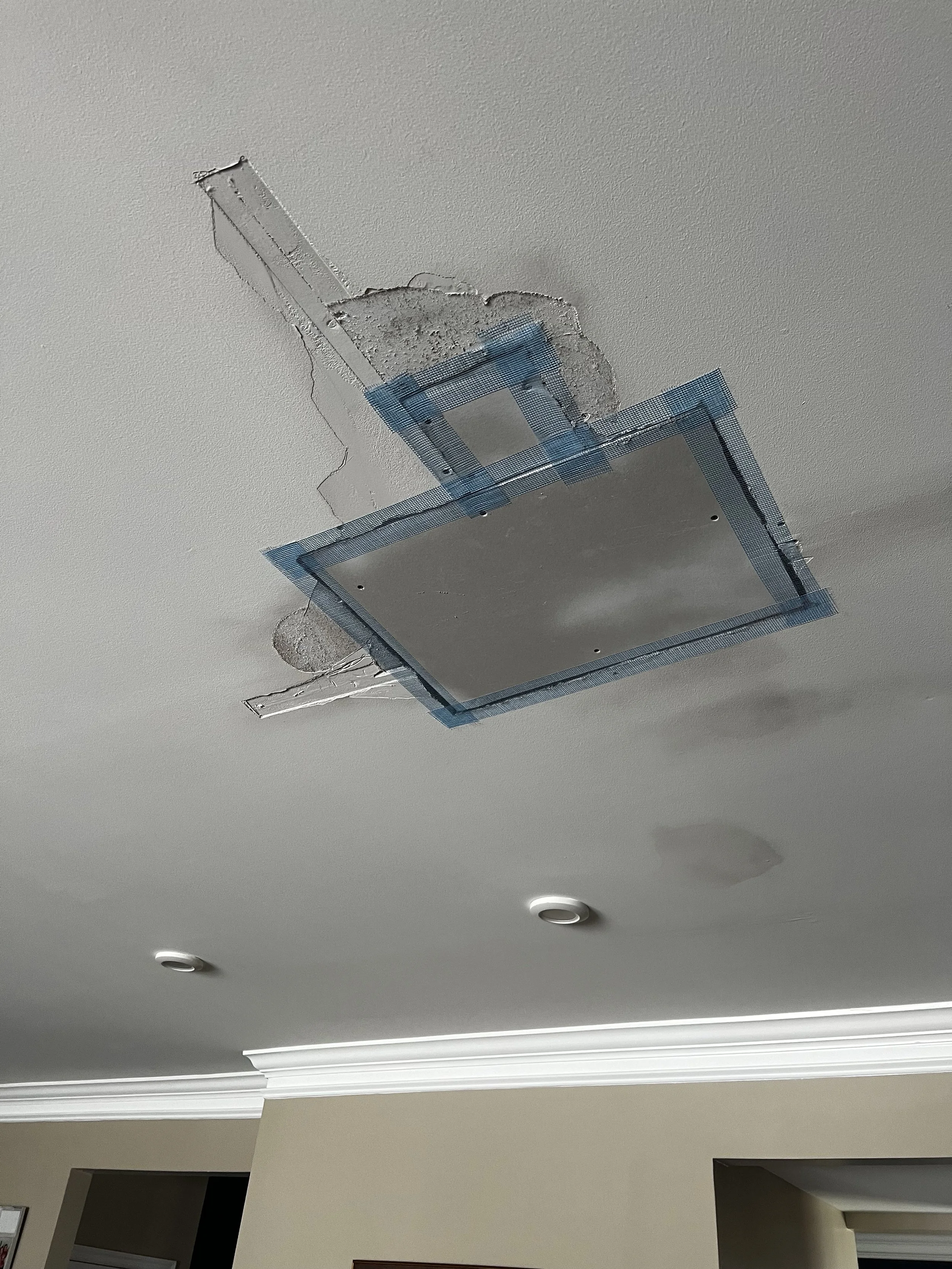 Ceiling with recessed lighting and an opening for a light fixture, with some parts being unfinished or under renovation.
