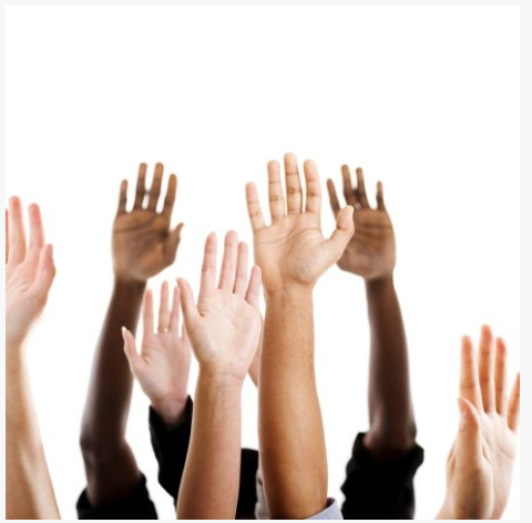 Multiple hands raised in the air, diverse in skin tone.