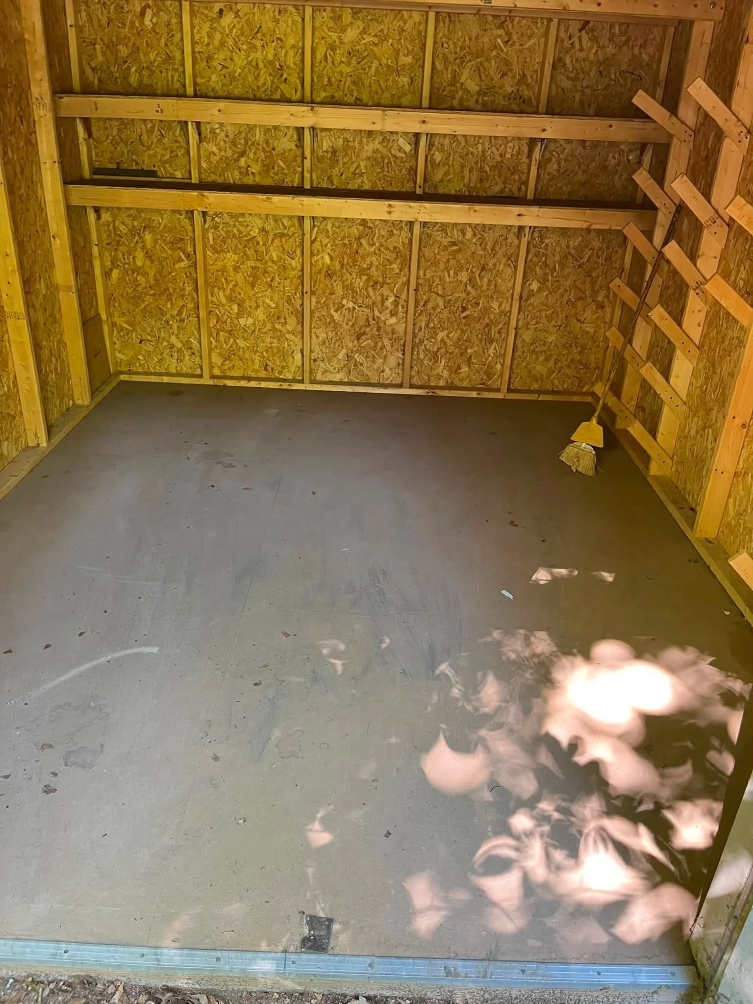 A construction site with an unfinished wooden wall, a broom leaning against the wall, and a flame near the bottom right corner.