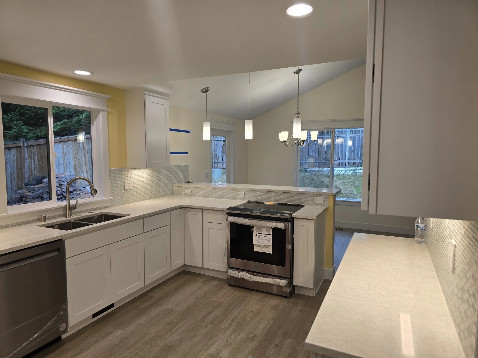Kitchen with white cabinets, stainless steel oven, granite countertops, and a window overlooking a fenced backyard.